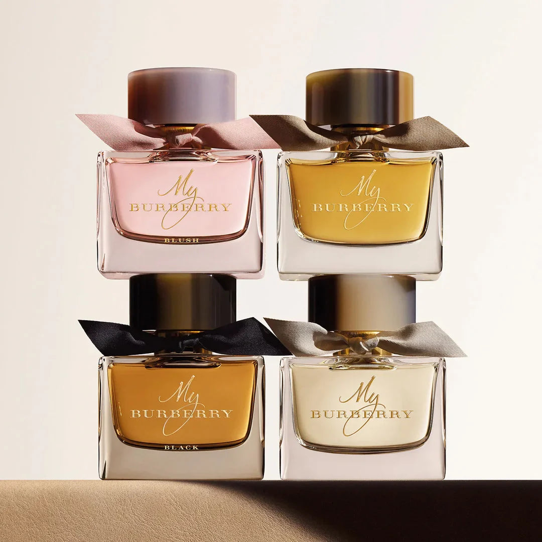 Quatro frascos do perfume My Burberry dispostos em duas fileiras, com tons de rosa, âmbar, dourado e bege, cada um com laço de tecido, em fundo suave e iluminado.