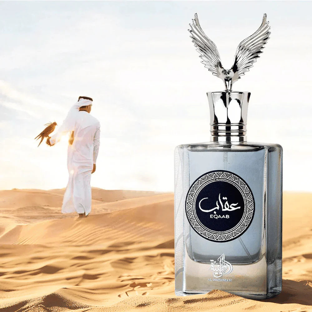 Frasco do perfume EQAAB da Al Wataniah em primeiro plano sobre as dunas do deserto, com design prateado e tampa em forma de águia com asas abertas. Ao fundo, homem trajando roupa tradicional árabe caminha segurando um falcão, cena imponente e cultural.