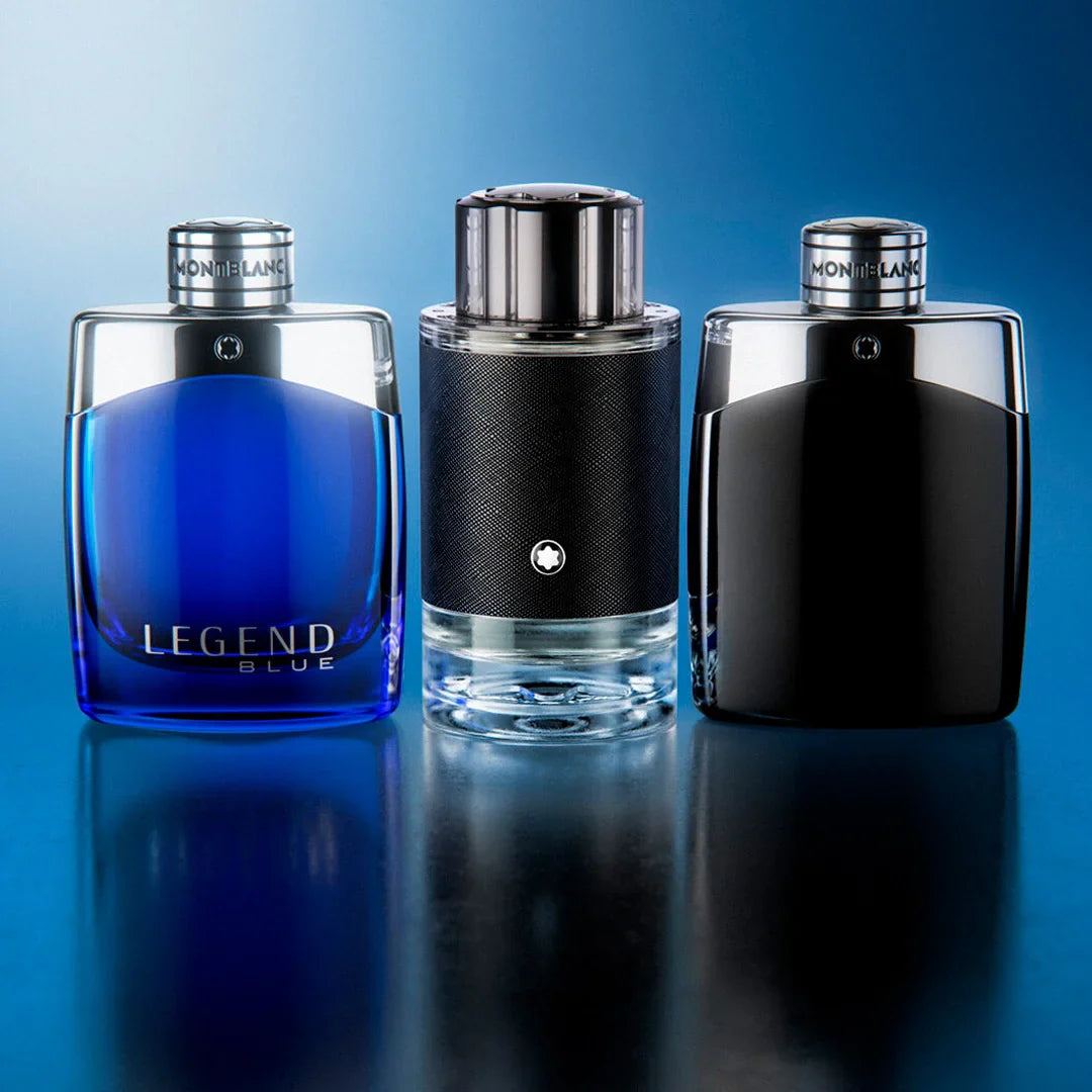 Trio de perfumes Montblanc Legend: azul, preto e cinza, posicionados lado a lado sobre superfície refletiva azul, simbolizando elegância, poder e estilo masculino.