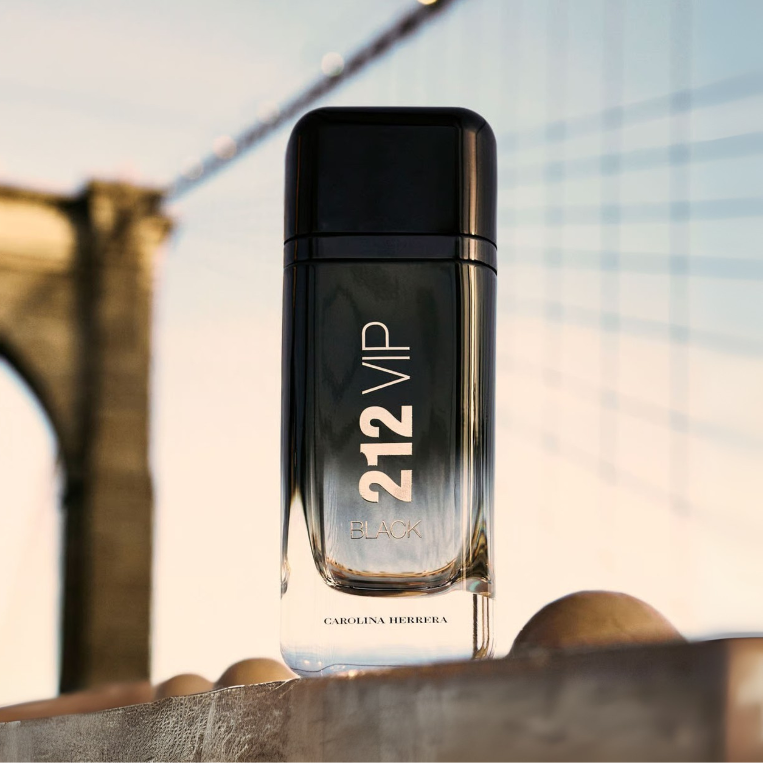 Perfume importado masculino 212 VIP Black Carolina Herrera em ambiente urbano noturno com uma ponte icônica ao fundo, simbolizando a vida noturna de Nova York e o homem VIP, disponível na Velyre.