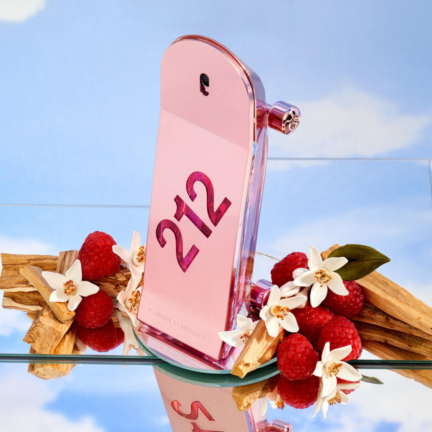 Perfume feminino 212 Heroes For Her Carolina Herrera em cenário vibrante com framboesas vermelhas, flores brancas e pedaços de madeira, sugerindo notas frutadas e frescas da fragrância.