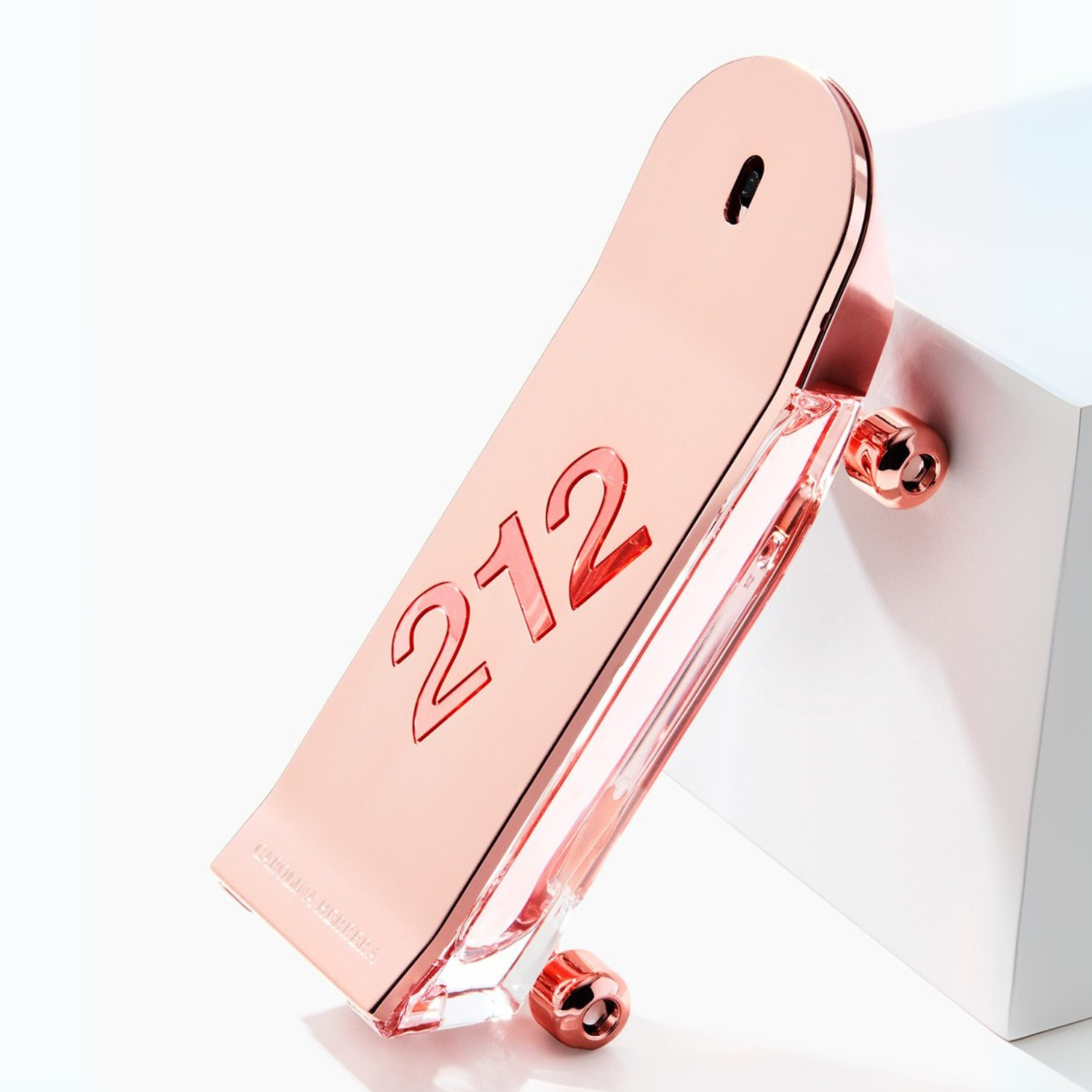 Perfume 212 Heroes For Her Carolina Herrera em ângulo dinâmico sobre fundo branco e bloco, destacando a inclinação do frasco e seu formato criativo de skate.