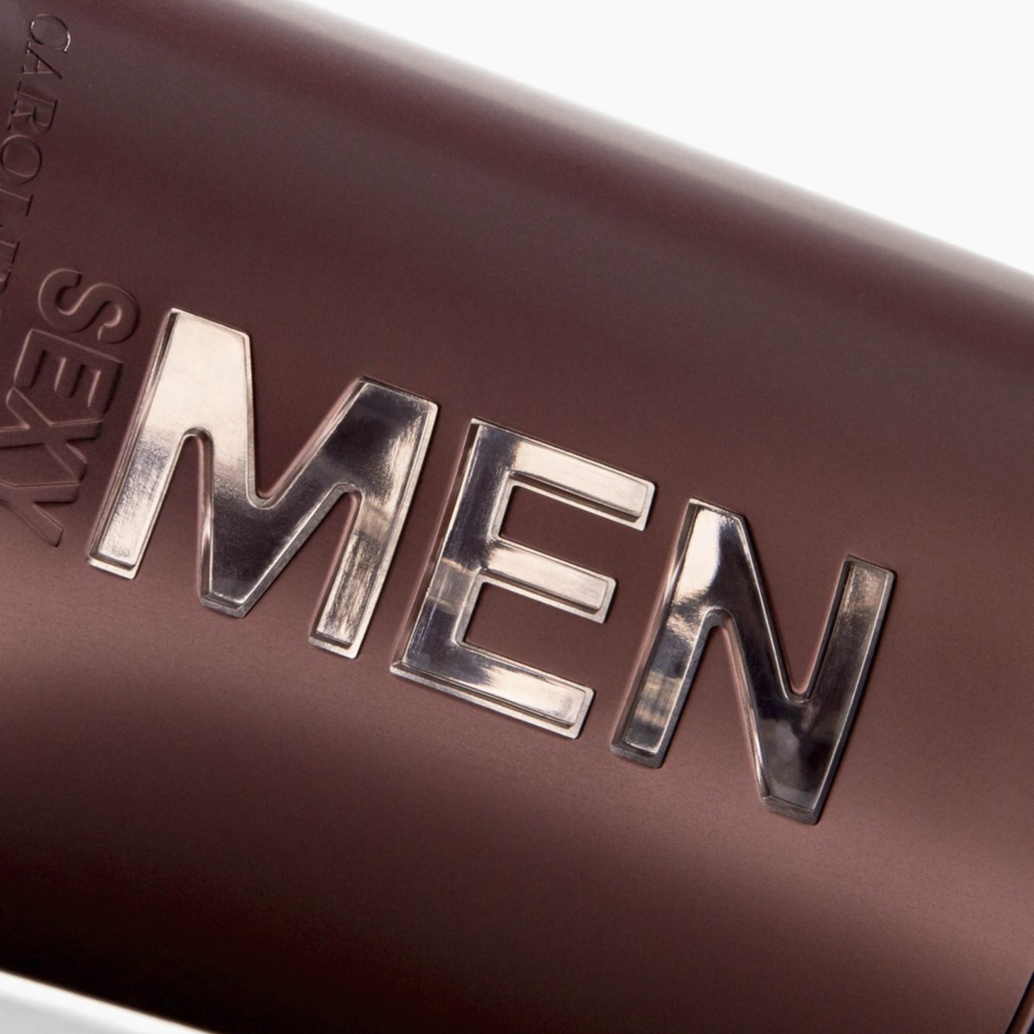 Close-up do frasco do perfume 212 Sexy Men Carolina Herrera, destacando as letras "MEN" em relevo e a textura do frasco marrom avermelhado, realçando a marca e o design.