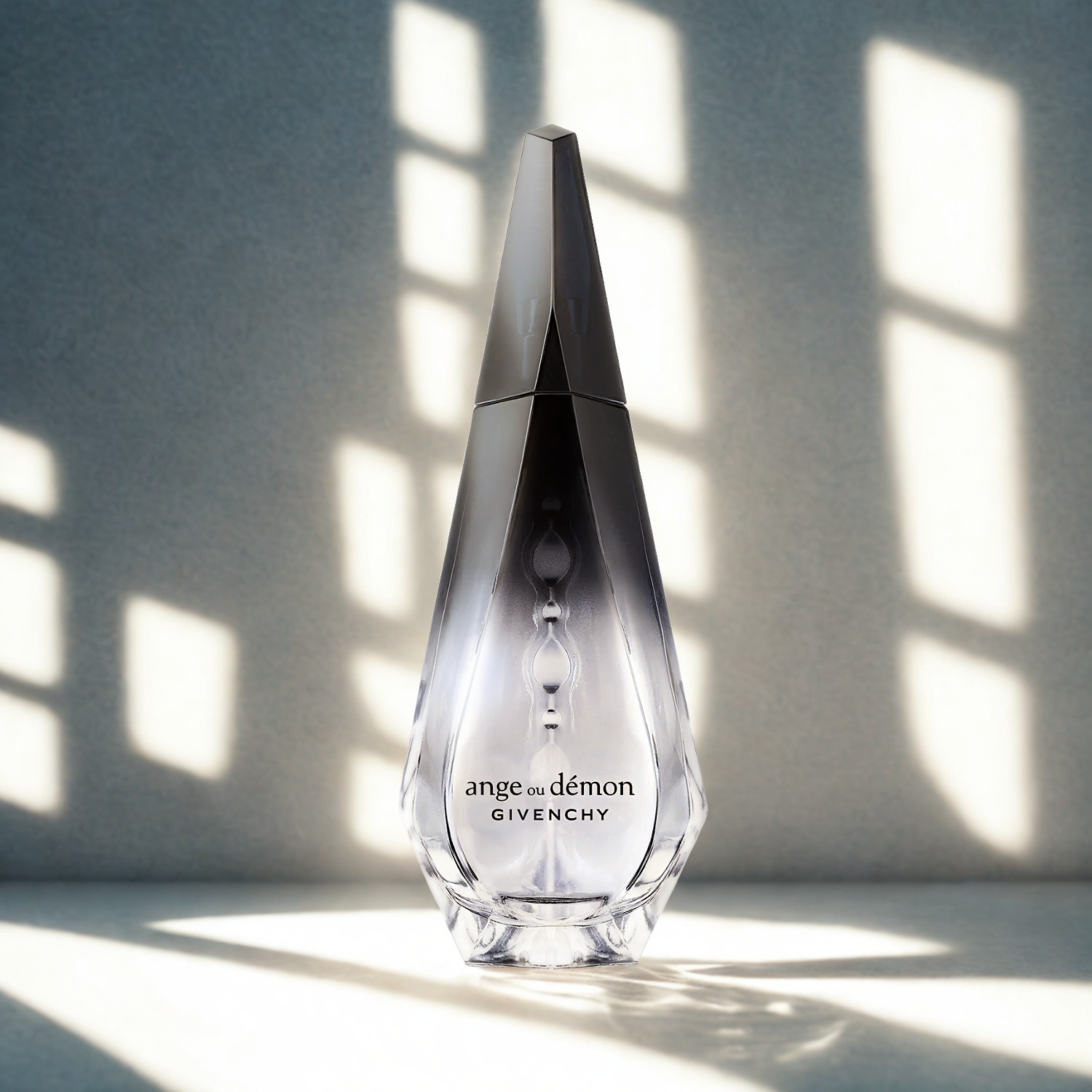 Perfume feminino Ange ou Démon Givenchy em destaque em um ambiente minimalista com jogo de luz e sombra dramático, realçando o formato único do frasco e seu mistério.