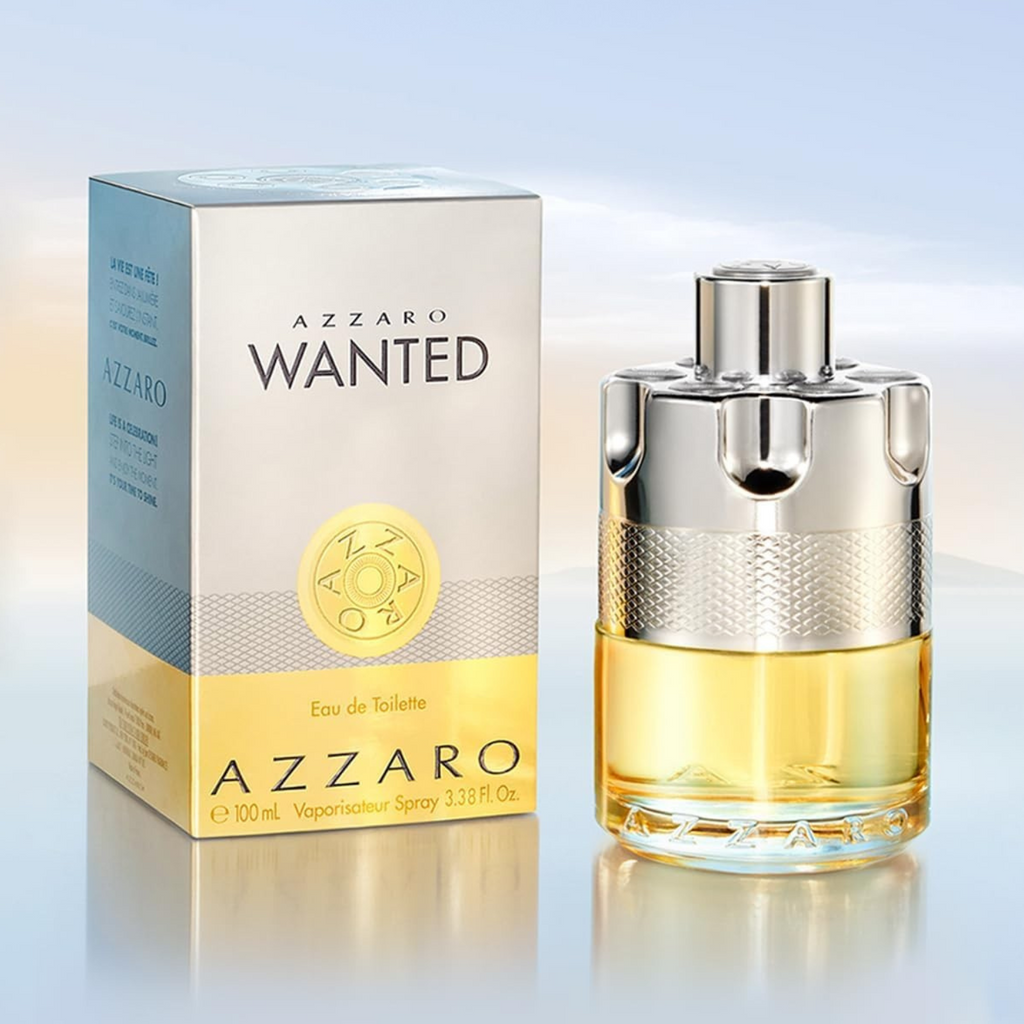 Perfume Azzaro Wanted ao lado da embalagem. O frasco dourado com tampa metálica está à direita, e a caixa prata e dourada com logotipo em relevo aparece à esquerda, sobre fundo claro.