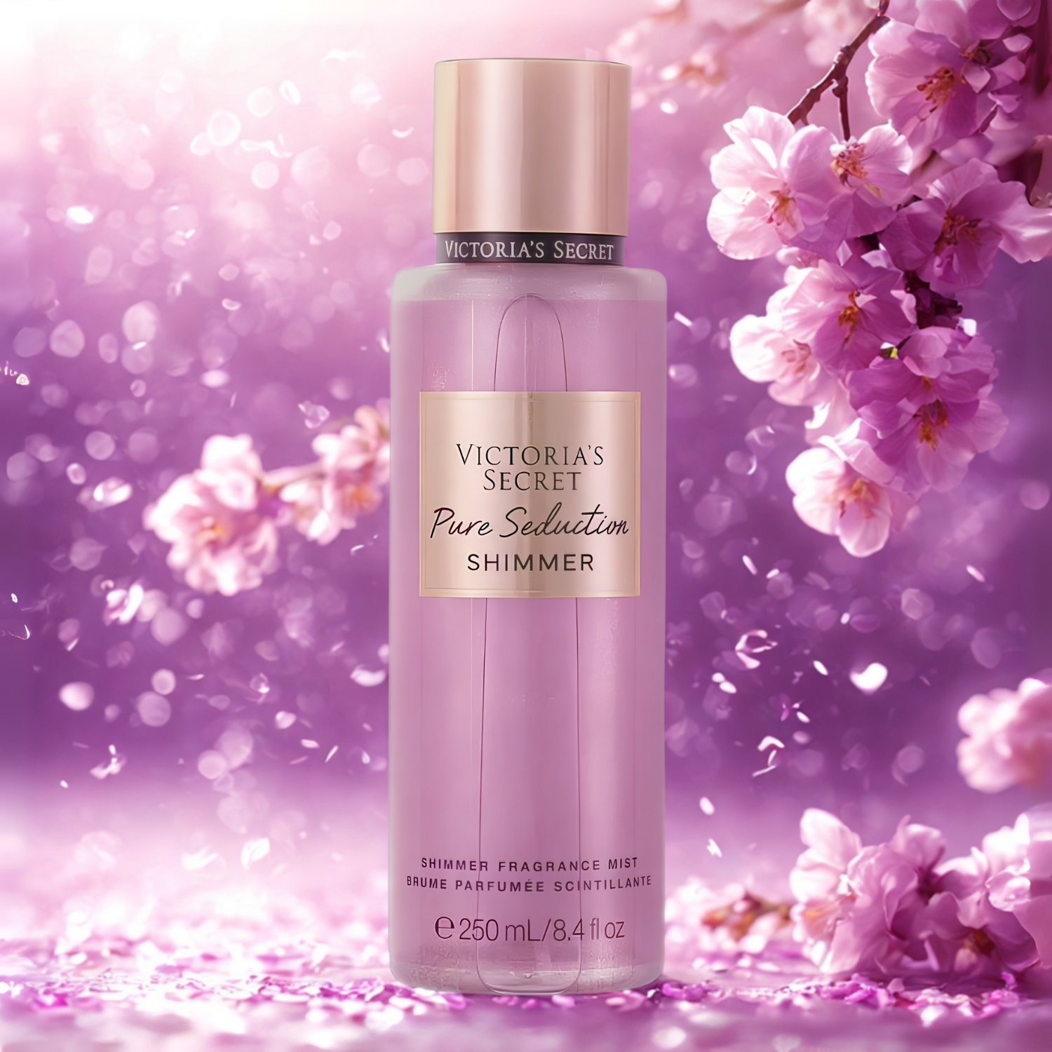 Frasco do body splash importado Pure Seduction Shimmer Victoria's Secret em destaque em um ambiente romântico com flores de cerejeira roxas e brilhos cintilantes ao fundo, evocando uma fragrância floral frutada e luminosa, disponível na Velyre.