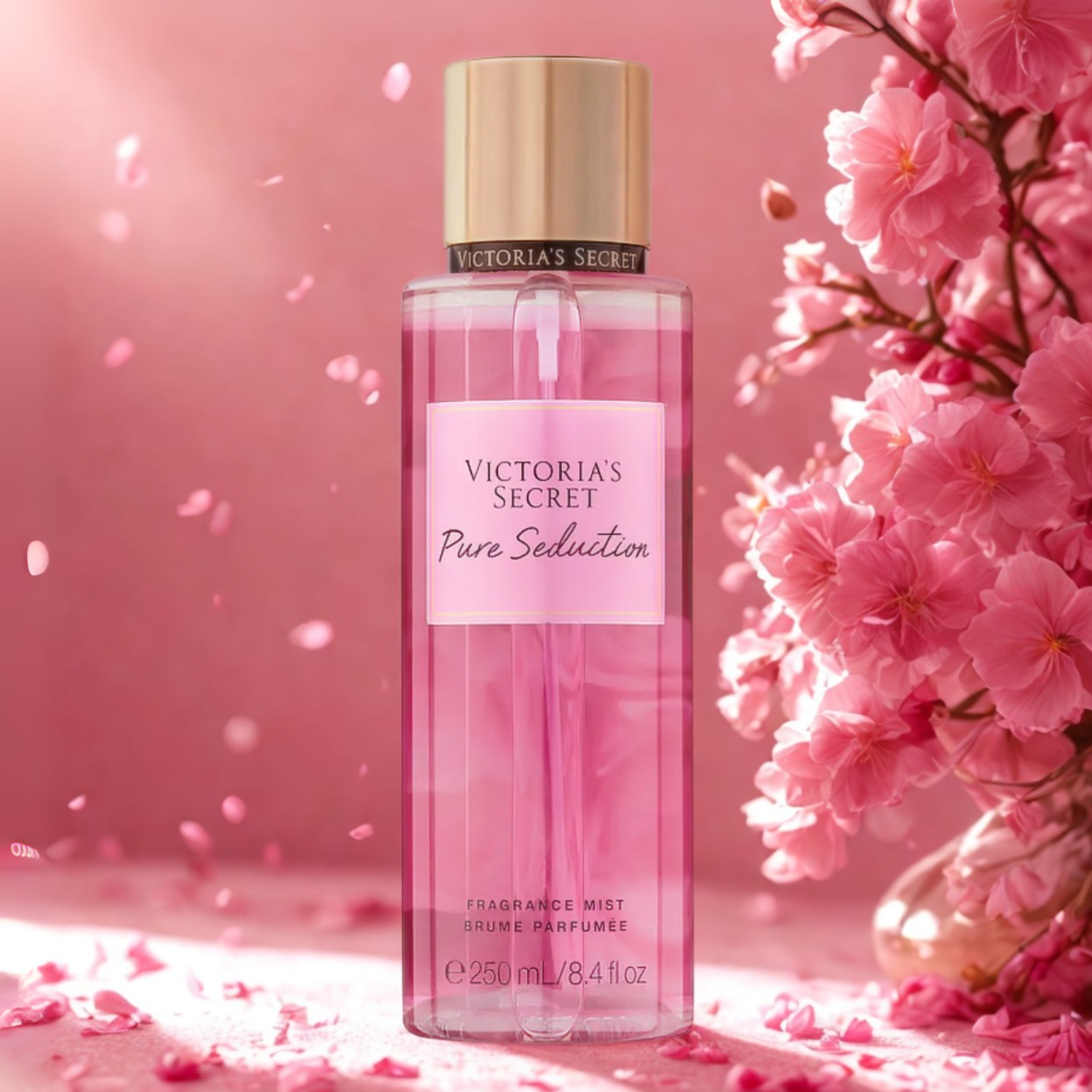 Frasco do body splash importado Pure Seduction Victoria's Secret em destaque em um ambiente romântico com flores cor-de-rosa e brilhos cintilantes ao fundo, evocando uma fragrância floral frutada e sedutora, disponível na Velyre.