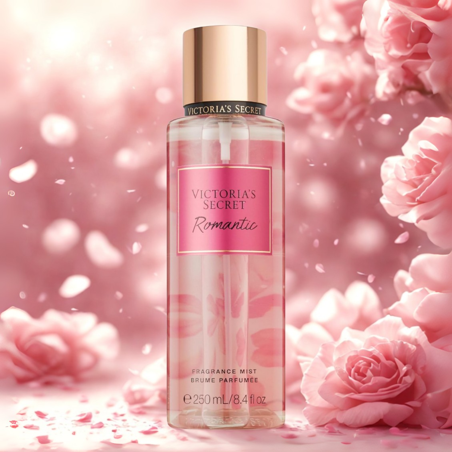 Frasco do body splash importado Romantic Victoria's Secret em destaque em um ambiente romântico com rosas cor-de-rosa em flor e pétalas caindo, evocando uma fragrância floral e delicada, disponível na Velyre.