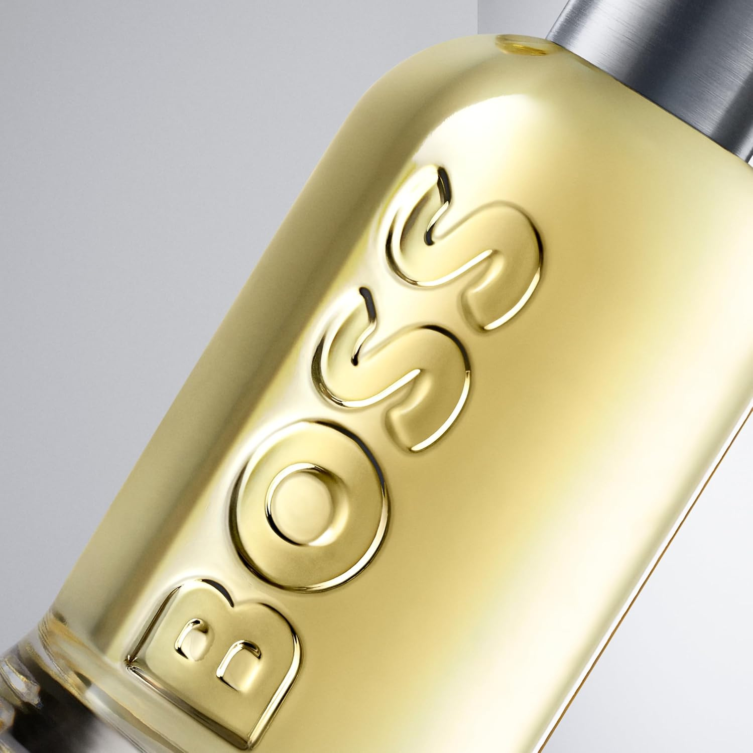 Close-up do frasco do Boss Bottled com o nome da marca em relevo e líquido dourado em destaque.