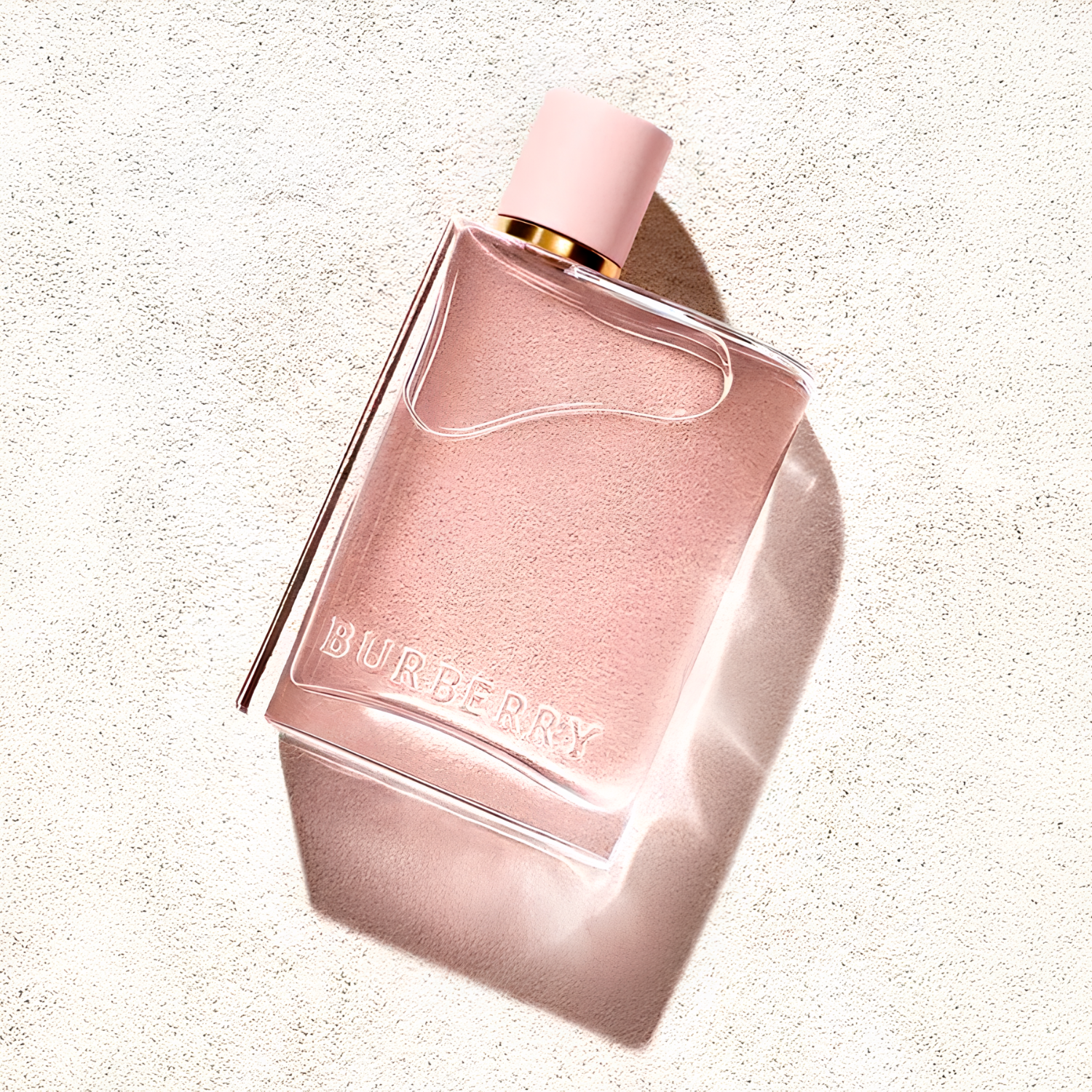 Frasco Burberry Her iluminado diretamente, deitado sobre fundo claro, com brilho intenso realçando a tampa rosa e o líquido em tom rosa suave.