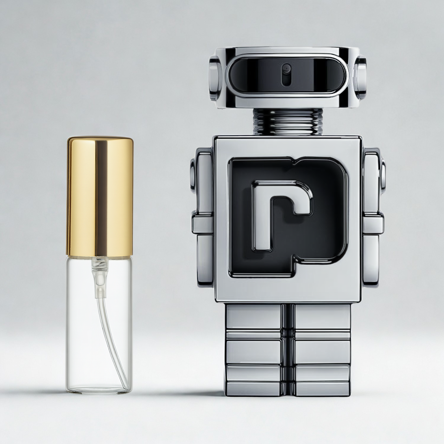 Decant de 5ml com borrifador dourado ao lado do frasco original do perfume importado masculino Phantom Rabanne Eau de Toilette, ambos sobre uma superfície e fundo cinza claro. A imagem destaca a apresentação do decant para venda e a familiaridade com o frasco original, disponíveis na Velyre.