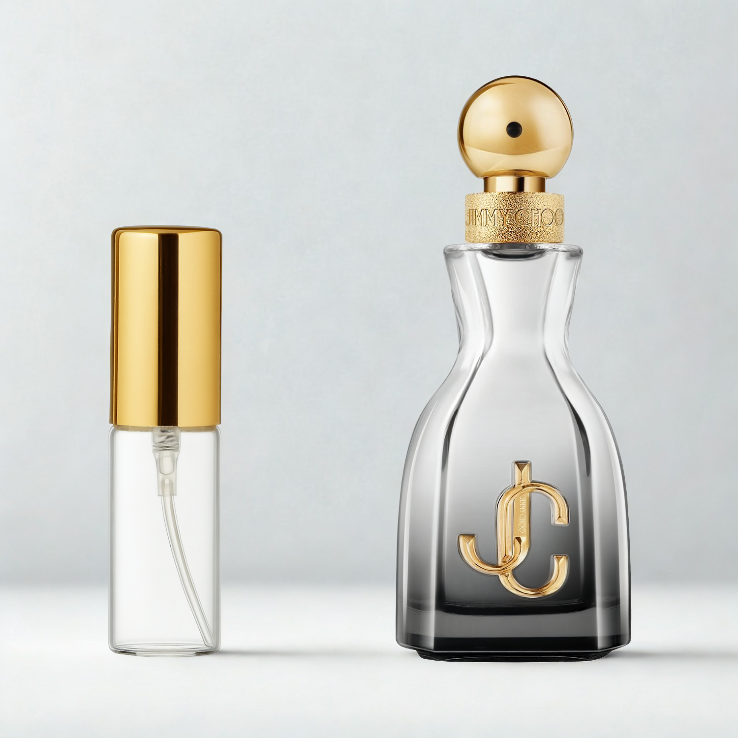 Decant de 5ml com borrifador dourado ao lado do frasco original do perfume importado feminino I Want Choo Forever Jimmy Choo Eau de Parfum, ambos sobre uma superfície e fundo cinza claro. A imagem destaca a apresentação do decant para venda e a familiaridade com o frasco original, disponíveis na Velyre.