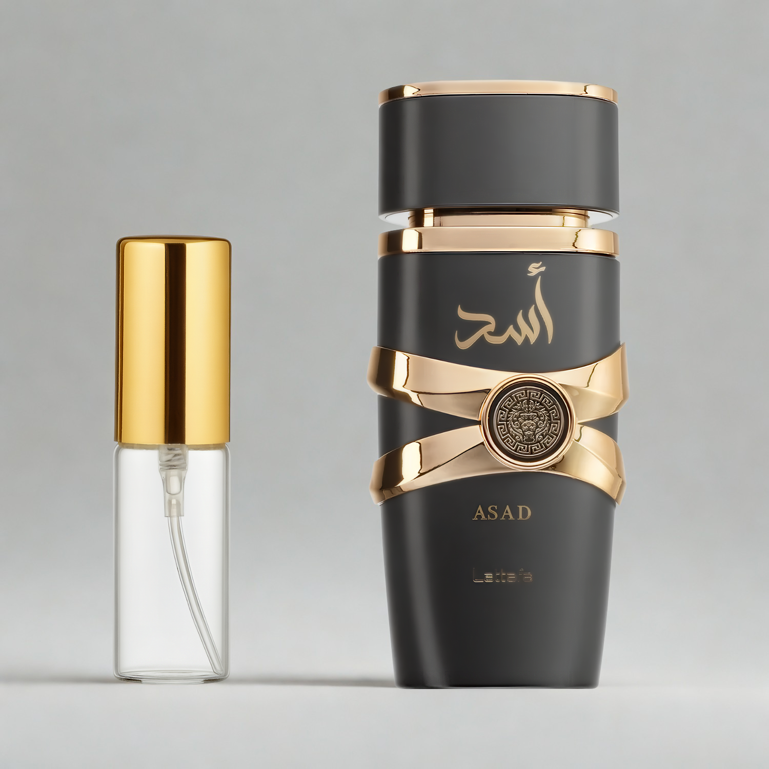 Decant de 5ml com borrifador dourado ao lado do frasco original do perfume árabe masculino Asad Lattafa Eau de Parfum, ambos sobre uma superfície e fundo cinza claro. A imagem destaca a apresentação do decant para venda e a familiaridade com o frasco original, disponíveis na Velyre.