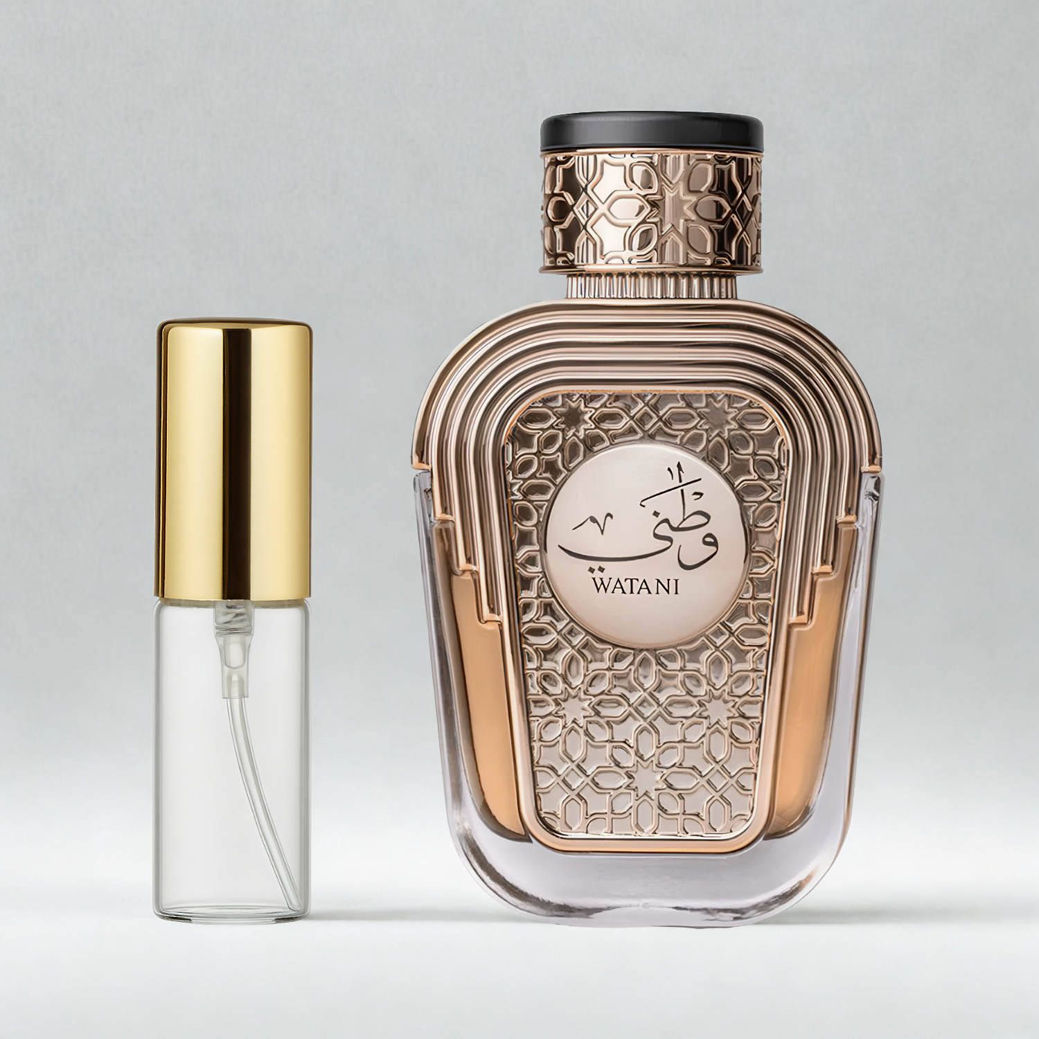Decant de 5ml com borrifador dourado ao lado do frasco original do perfume árabe Watani Al Wataniah Eau de Parfum, ambos sobre uma superfície e fundo cinza claro. A imagem destaca a apresentação do decant para venda e a familiaridade com o frasco original, disponíveis na Velyre.