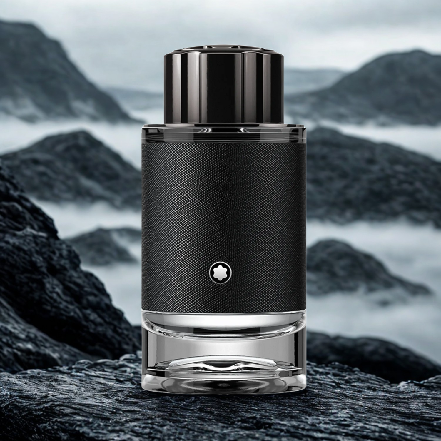 Perfume masculino Explorer Montblanc em destaque sobre uma rocha em um cenário de montanhas escuras cobertas por névoa, evocando uma fragrância para aventureiros e exploradores.
