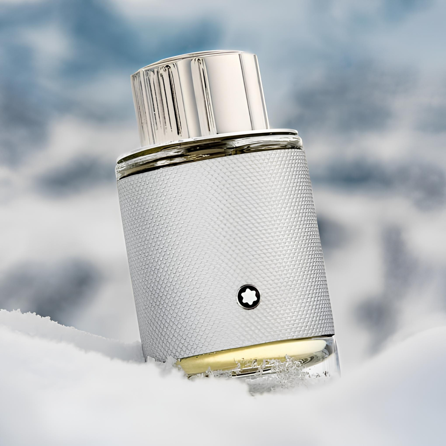 Frasco do Montblanc Explorer Platinum parcialmente coberto por neve, com destaque para o corpo prateado texturizado e tampa metálica. A neve ao redor reforça a proposta fresca e gélida da fragrância.
