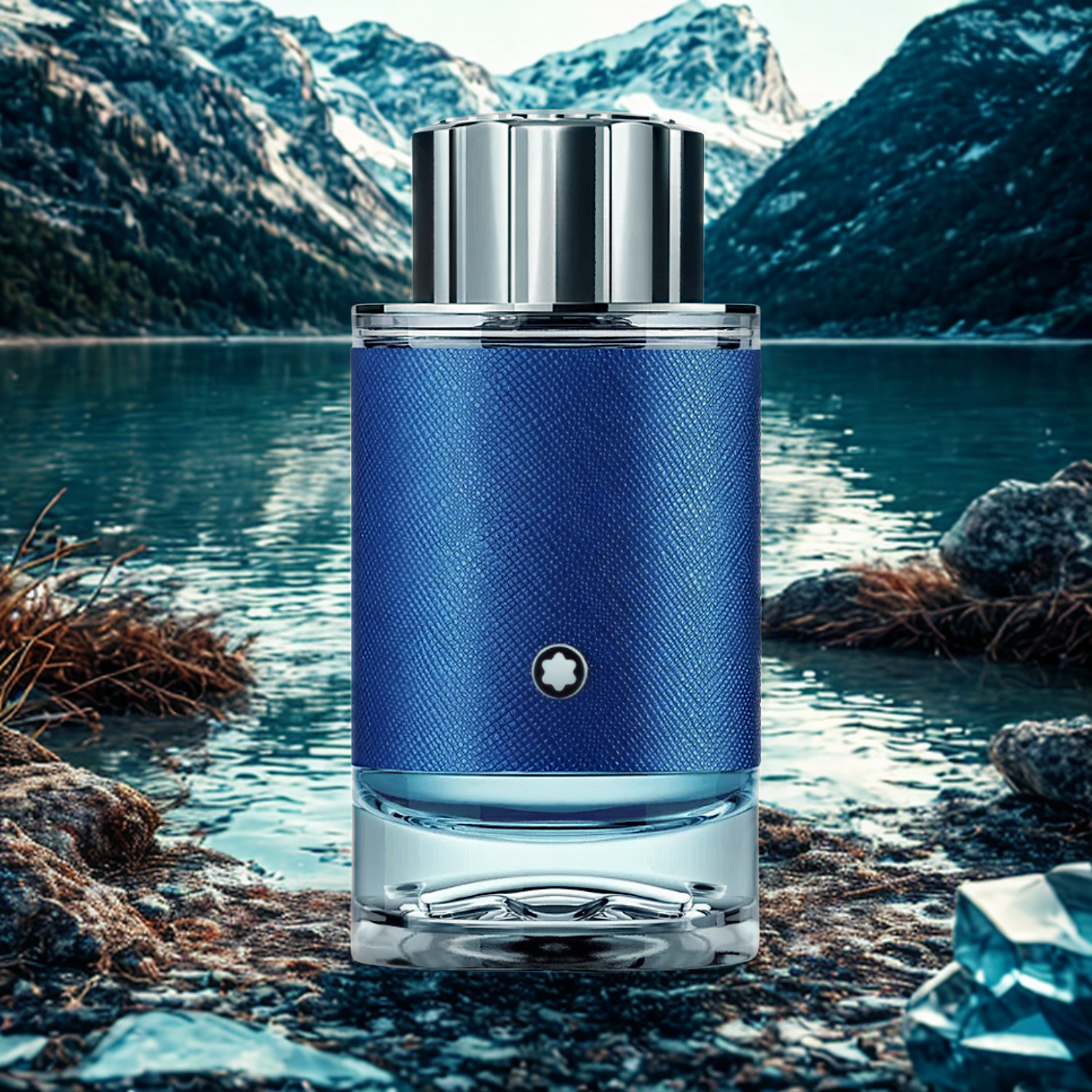 Perfume masculino Explorer Ultra Blue Montblanc em destaque na margem rochosa de um lago com águas calmas e montanhas imponentes ao fundo sob um céu claro, evocando uma sensação de aventura em paisagens aquáticas e montanhosas.