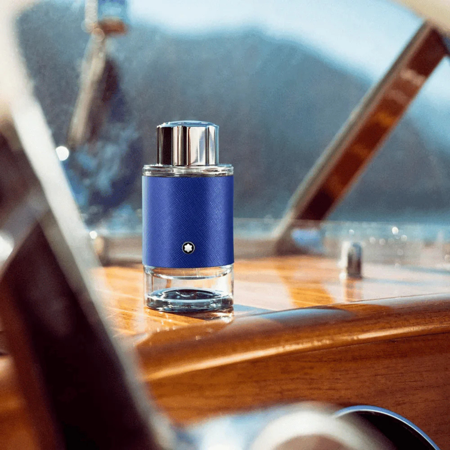 Perfume Explorer Ultra Blue Montblanc posicionado sobre uma superfície de madeira clara dentro de uma embarcação, com detalhes náuticos ao redor, transmitindo uma sensação de exploração marítima e frescor oceânico.
