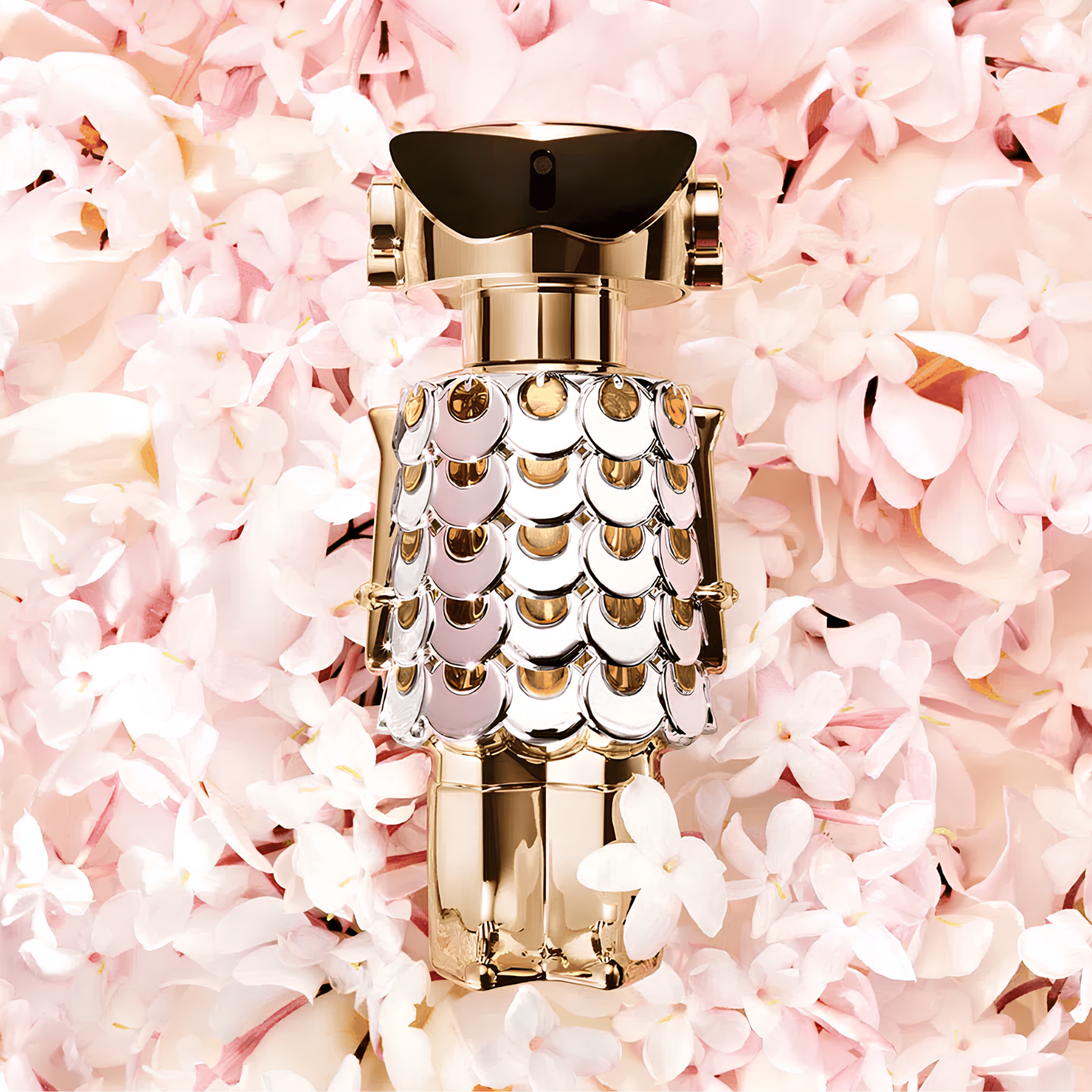 Perfume importado feminino Fame Rabanne em destaque em um ambiente delicado repleto de flores claras em tons de rosa e branco, sugerindo uma combinação de ousadia e feminilidade, disponível na Velyre.