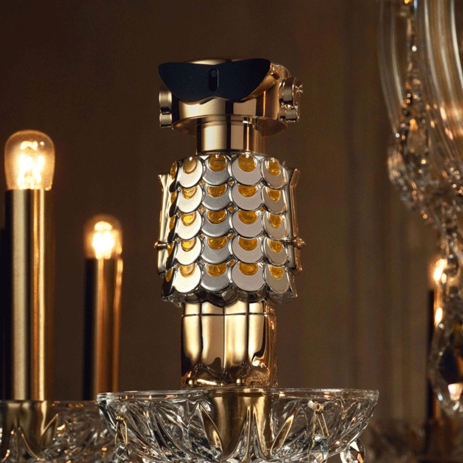 Perfume importado feminino Fame Rabanne posicionado sobre uma base de cristal transparente, com luzes douradas suaves e elementos decorativos clássicos ao fundo, transmitindo uma aura de glamour e sofisticação, disponível na Velyre.