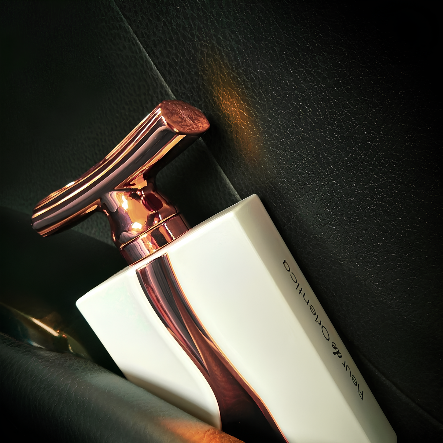 Perfume árabe Fleur de Orientica Al Haramain, disponível na Velyre, em ângulo sobre superfície escura e texturizada, realçando contraste do frasco branco com detalhe em ouro rosé e sofisticação da fragrância.