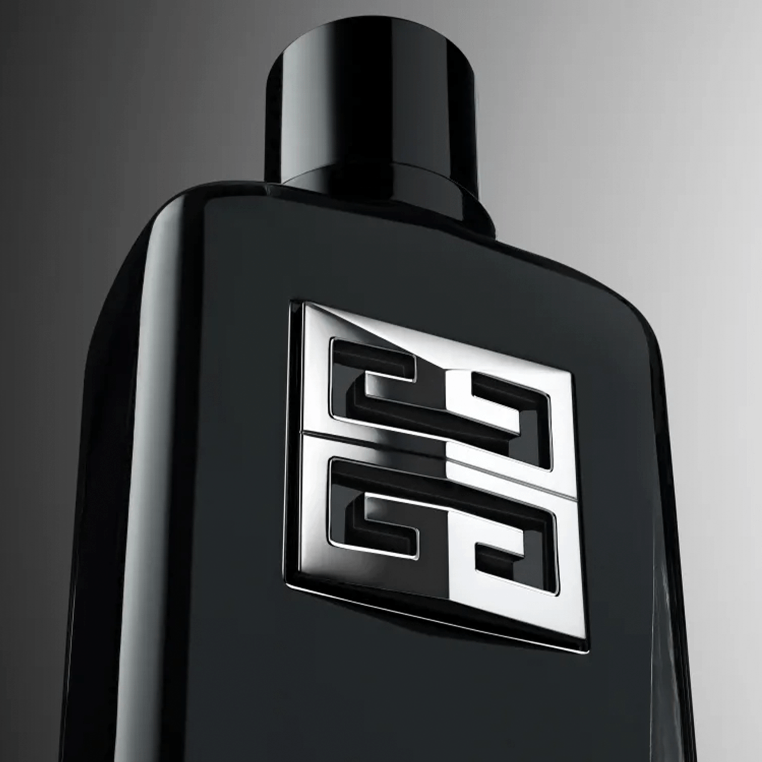 Close do perfume Givenchy Gentleman Society com destaque no logo prateado em alto-relevo e brilho sobre o vidro preto.