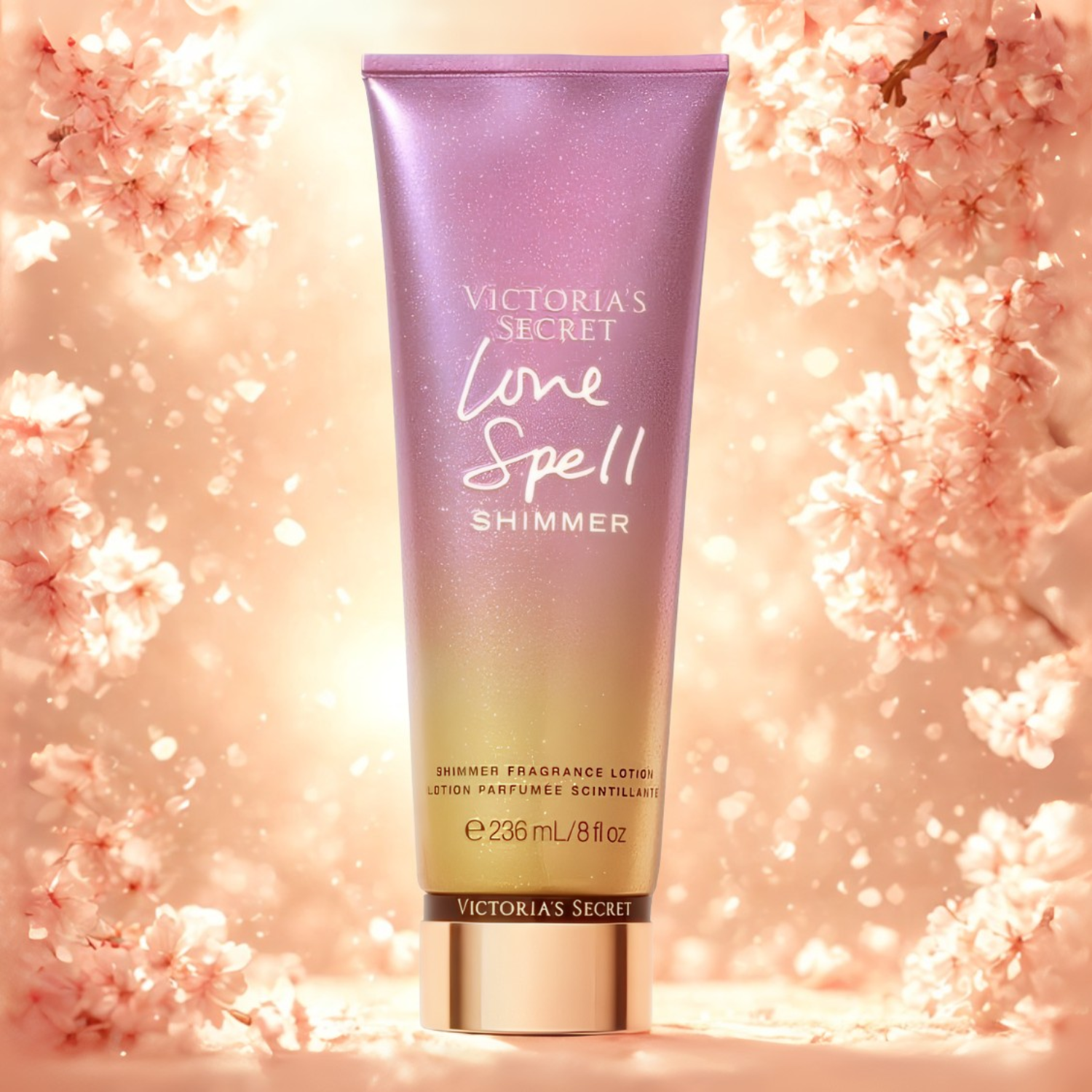 Tubo do hidratante perfumado importado Love Spell Shimmer Victoria's Secret em destaque em um ambiente romântico com flores de cerejeira e brilhos cor-de-rosa ao fundo, evocando uma fragrância floral doce e luminosa, disponível na Velyre.