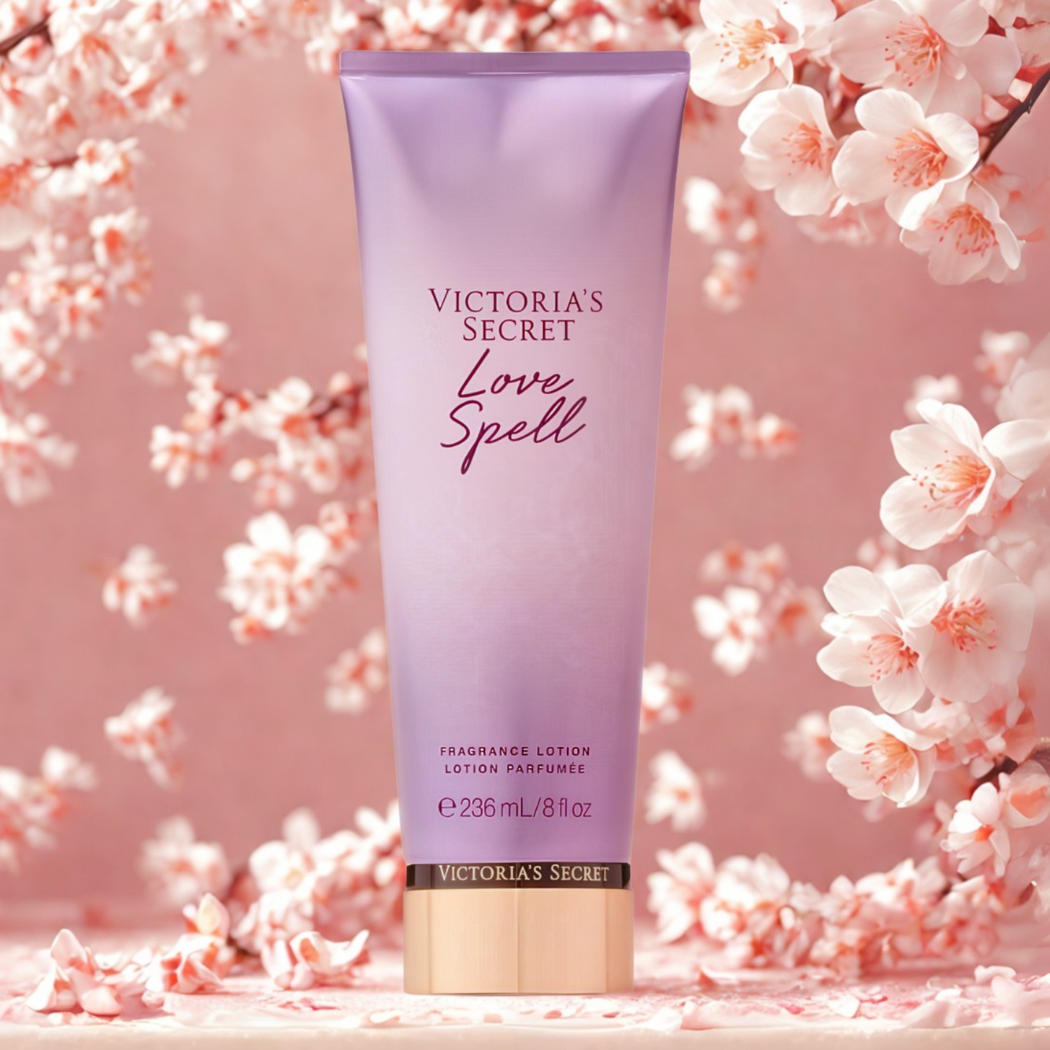 Tubo do hidratante perfumado importado Love Spell Victoria's Secret em destaque em um ambiente delicado com flores de cerejeira rosa e branca ao fundo, evocando uma fragrância floral doce e romântica, disponível na Velyre.