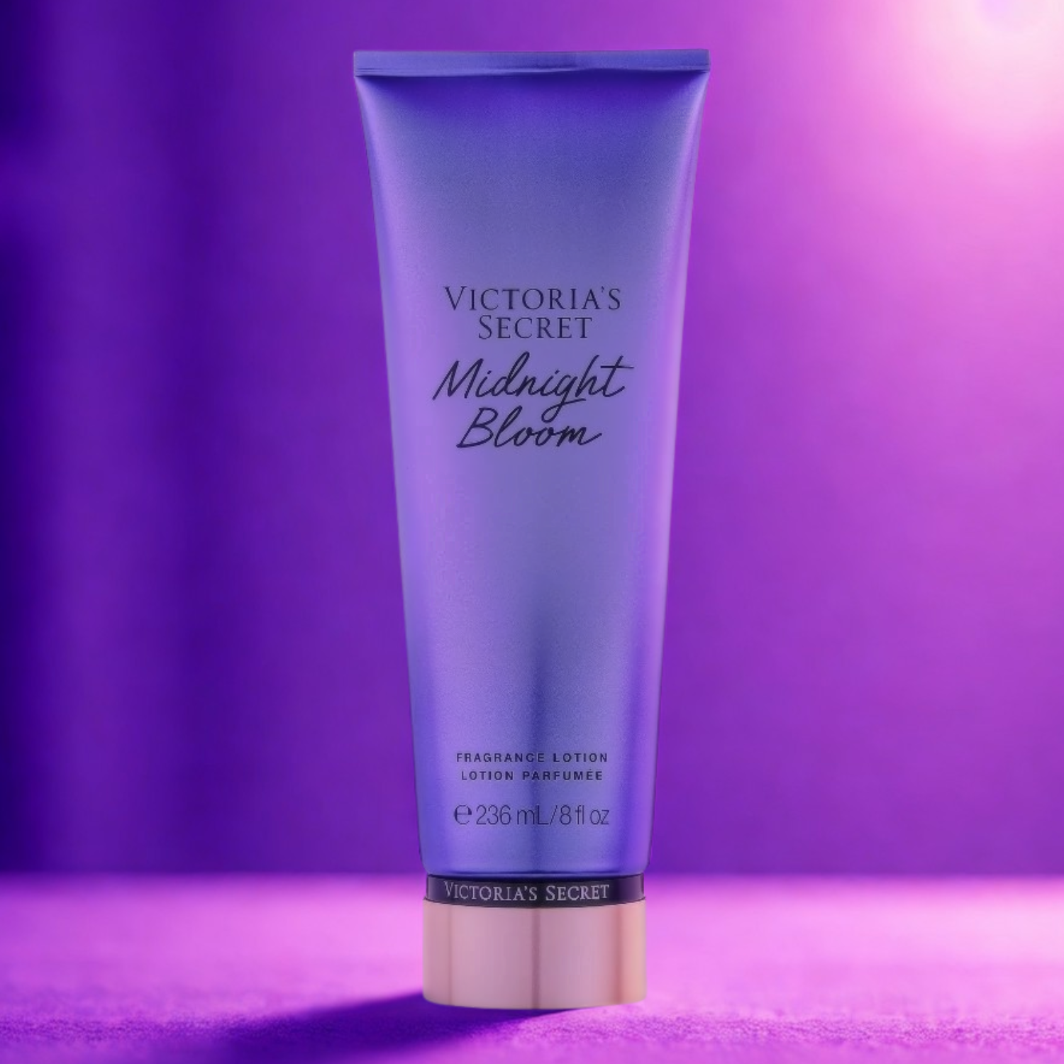 Tubo do hidratante perfumado importado Midnight Bloom Victoria's Secret em destaque sobre uma superfície roxa escura, com uma luz suave e misteriosa ao fundo, evocando uma fragrância floral noturna, disponível na Velyre.