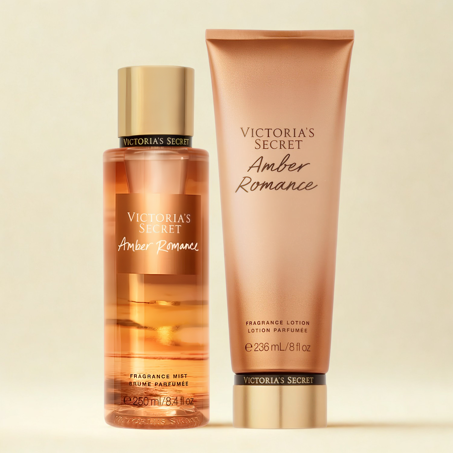 Kit de body splash e hidratante perfumado importado Amber Romance Victoria's Secret em close-up, disponíveis na Velyre. A imagem mostra os produtos sobre uma superfície clara, com o fundo suavemente desfocado e detalhes de galhos com bagas vermelhas.