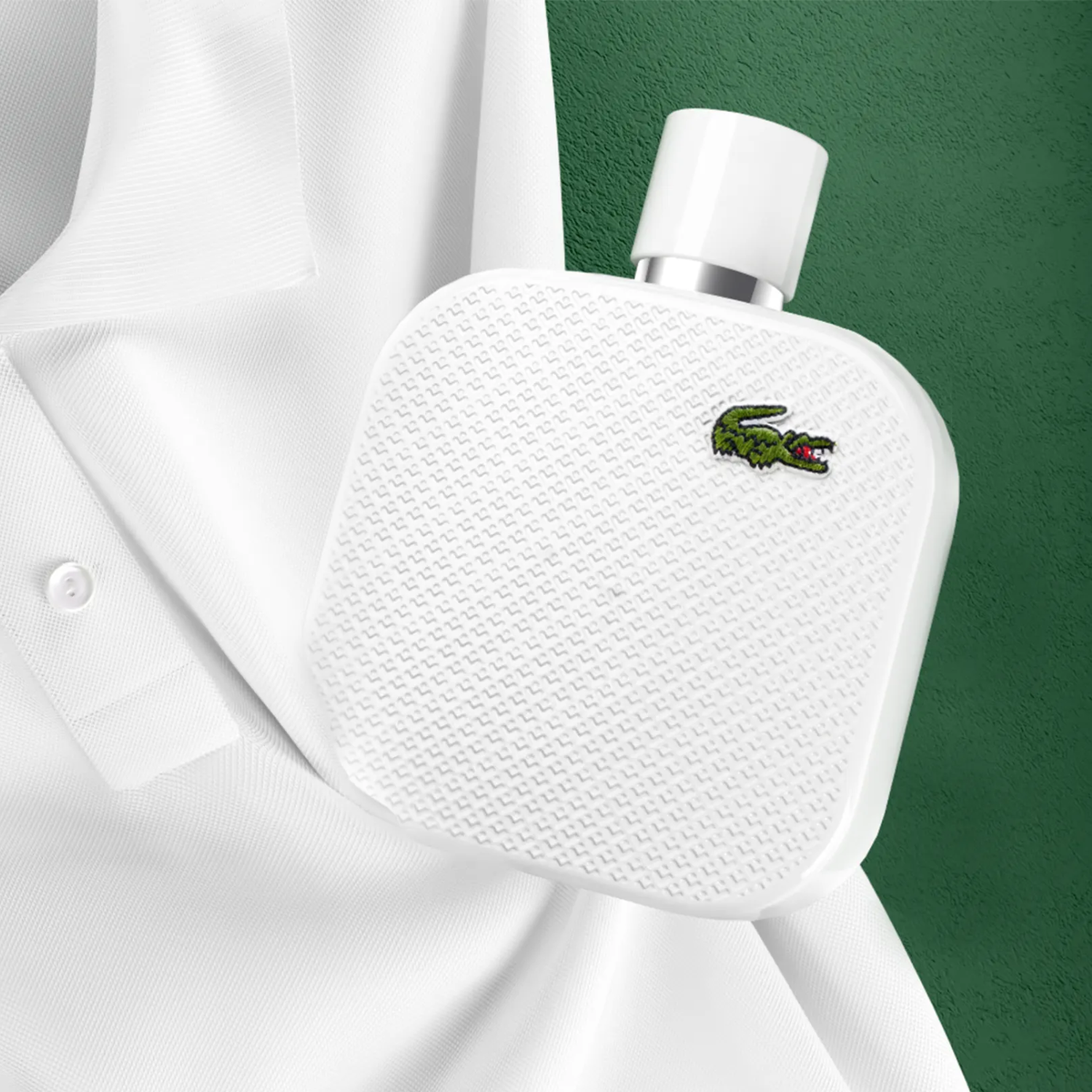 Frasco do perfume L.12.12 Blanc Lacoste posicionado ao lado de uma camisa polo branca da marca, em um fundo verde texturizado, reforçando a conexão da fragrância com o universo esportivo e elegante da Lacoste.