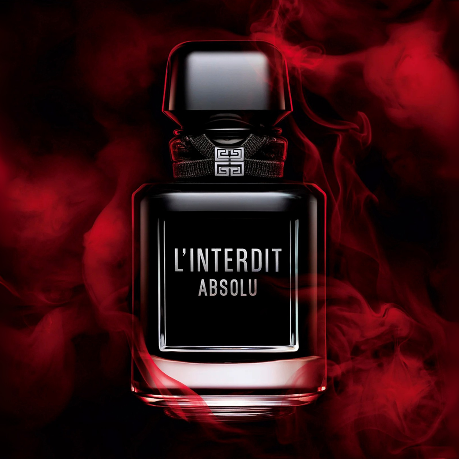 Perfume L’Interdit Absolu iluminado por fumaça vermelha, destacando o frasco preto com o nome da fragrância em branco e o logo metálico da Givenchy no colarinho.