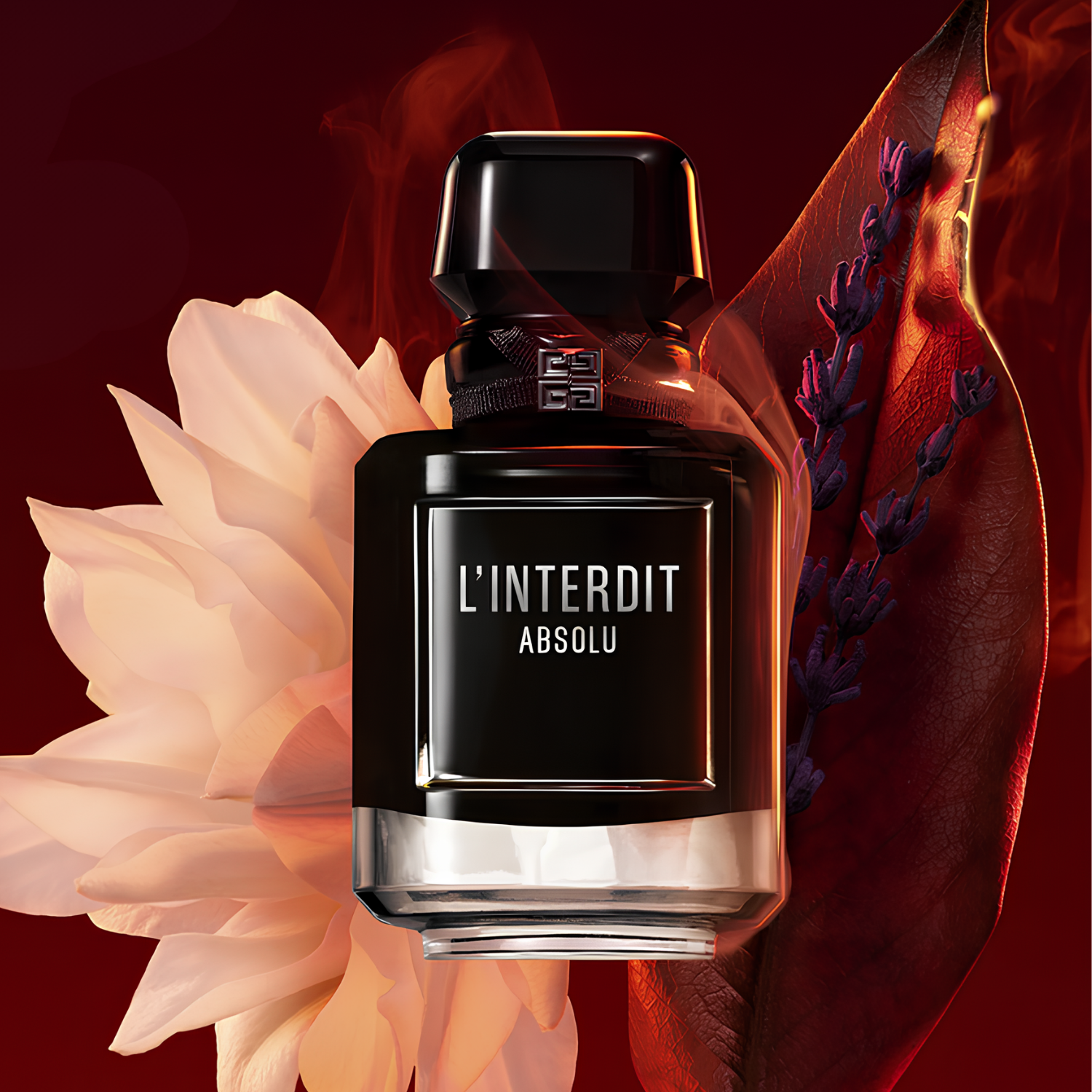 Frasco do L’Interdit Absolu rodeado por pétalas brancas e folhas vermelhas, com fundo vermelho escuro que destaca a intensidade da fragrância.