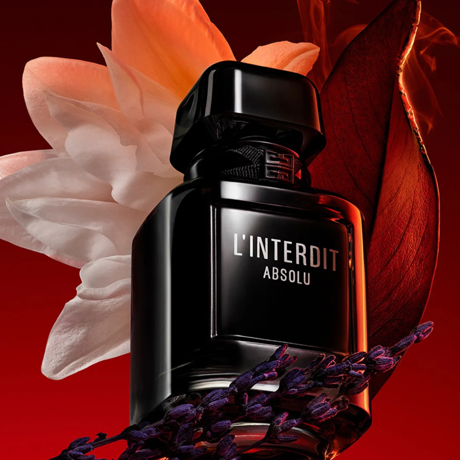 L’Interdit Absolu fotografado em ângulo dramático com flores claras e elementos botânicos ao fundo, transmitindo intensidade e elegância.