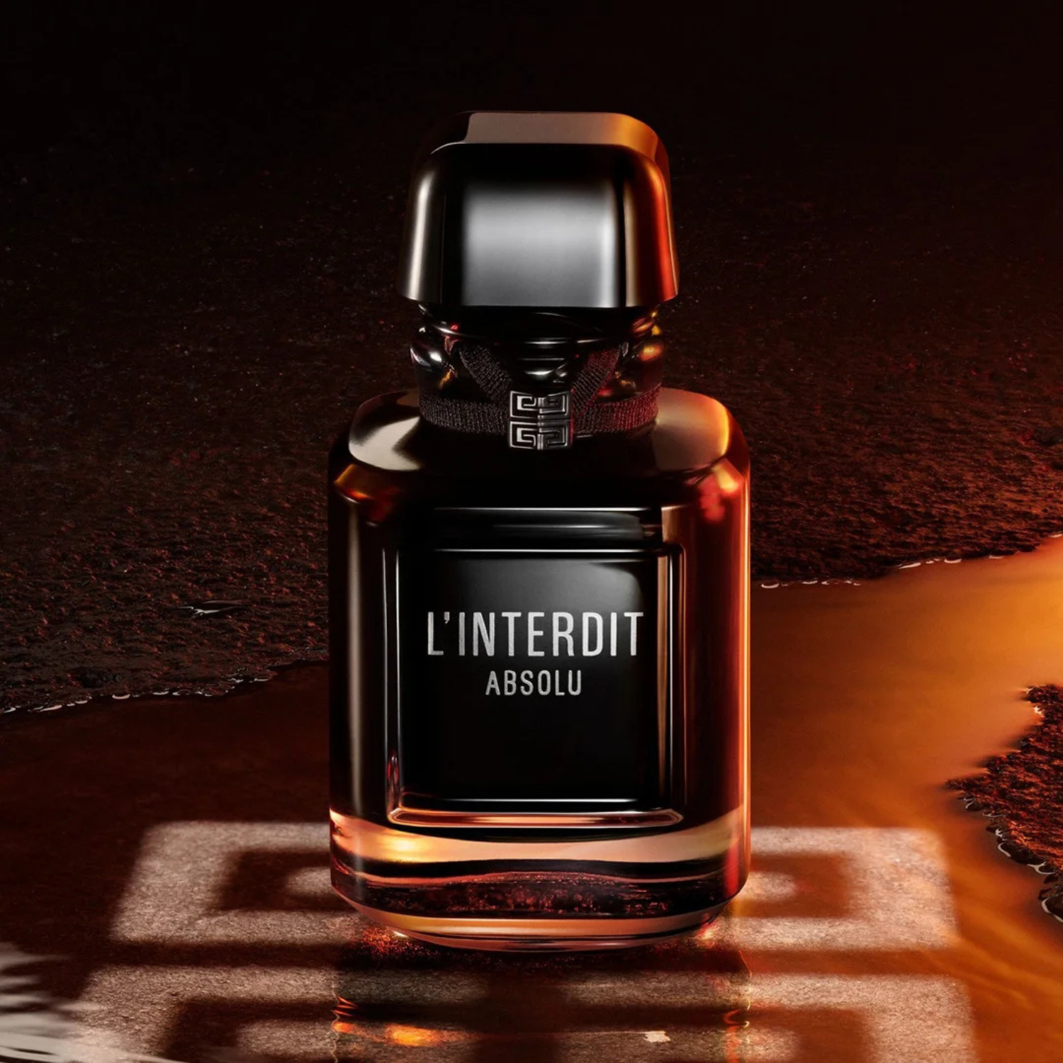 Frasco do perfume L’Interdit Absolu sobre superfície úmida com reflexo dourado, transmitindo uma atmosfera intensa e luxuosa.