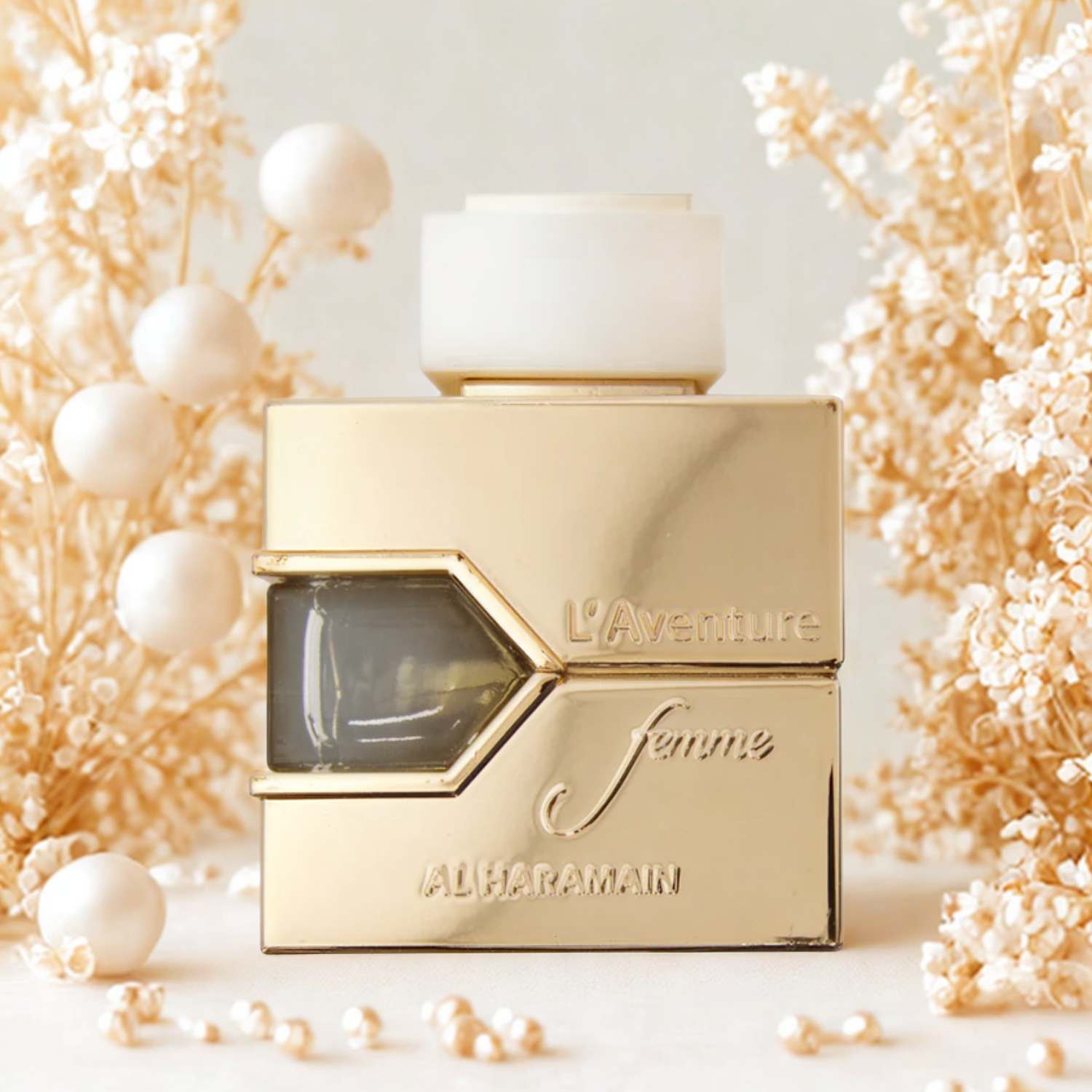 Perfume árabe L'aventure Femme Al Haramain cercado por pérolas brancas e pequenas flores secas em tons claros, disponível na Velyre, criando atmosfera delicada e romântica.