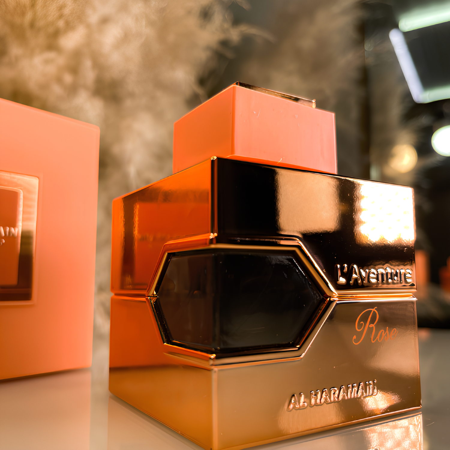 Perfume árabe L'aventure Rose Al Haramain ao lado de sua embalagem pêssego, também disponível na Velyre, refletindo o design do frasco e mostrando a apresentação completa.