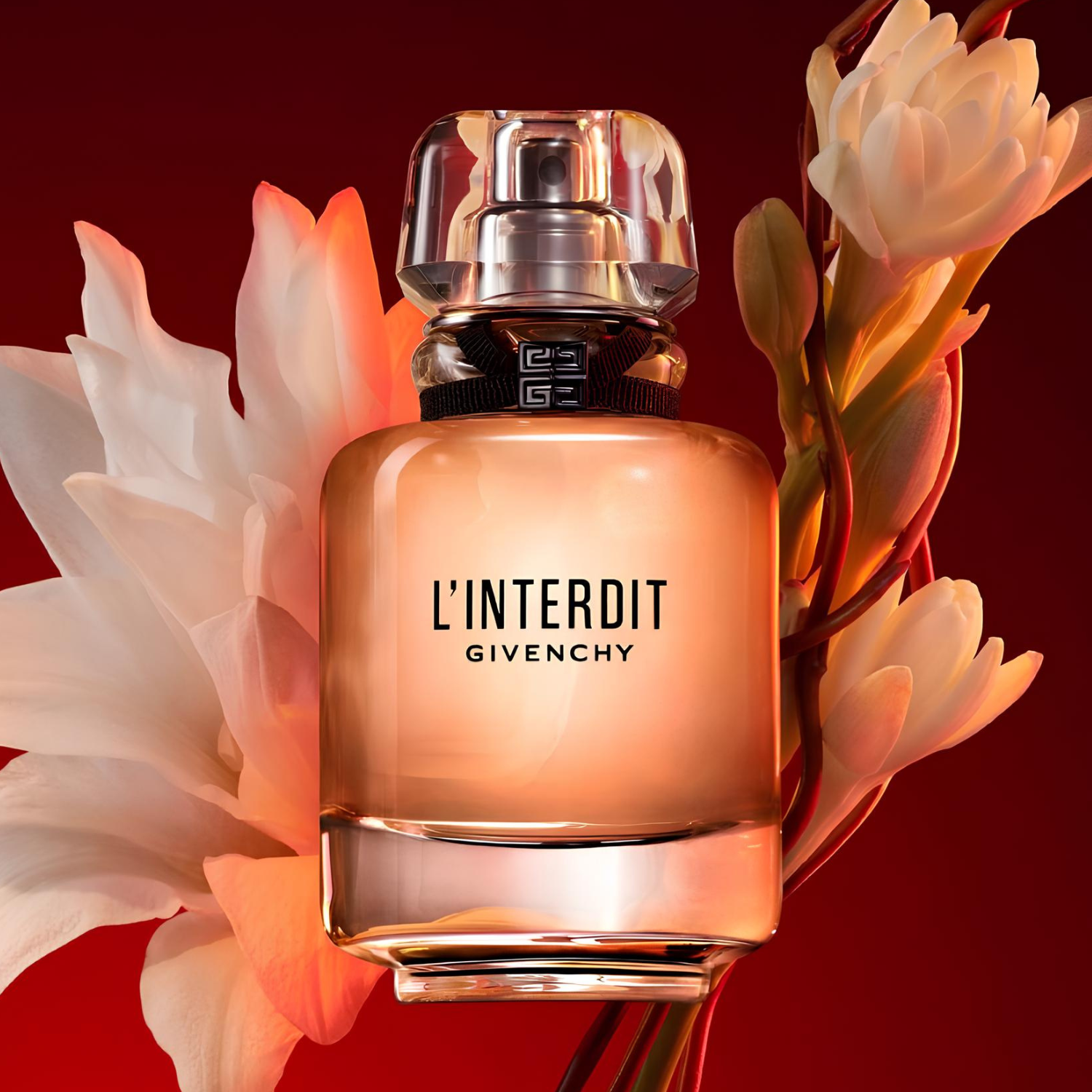 Frasco do L’Interdit Givenchy cercado por flores brancas em fundo vermelho intenso.