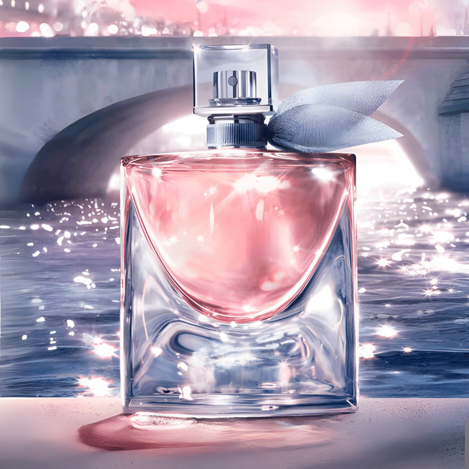 Perfume La Vie Est Belle diante de um rio cintilante ao entardecer, refletindo luz suave e fundo urbano.