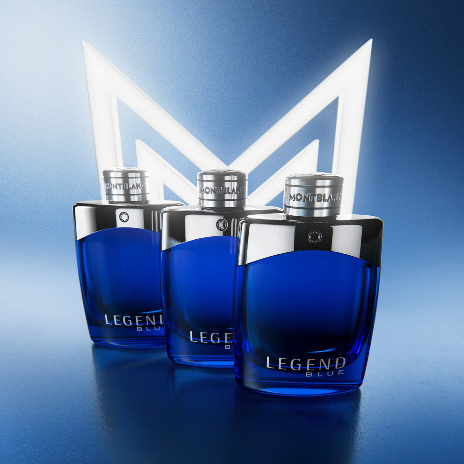 Vista superior de frascos do perfume Legend Blue Montblanc, com um deles flutuando, realçando o design das tampas prateadas e o jogo de reflexos em um fundo azul.