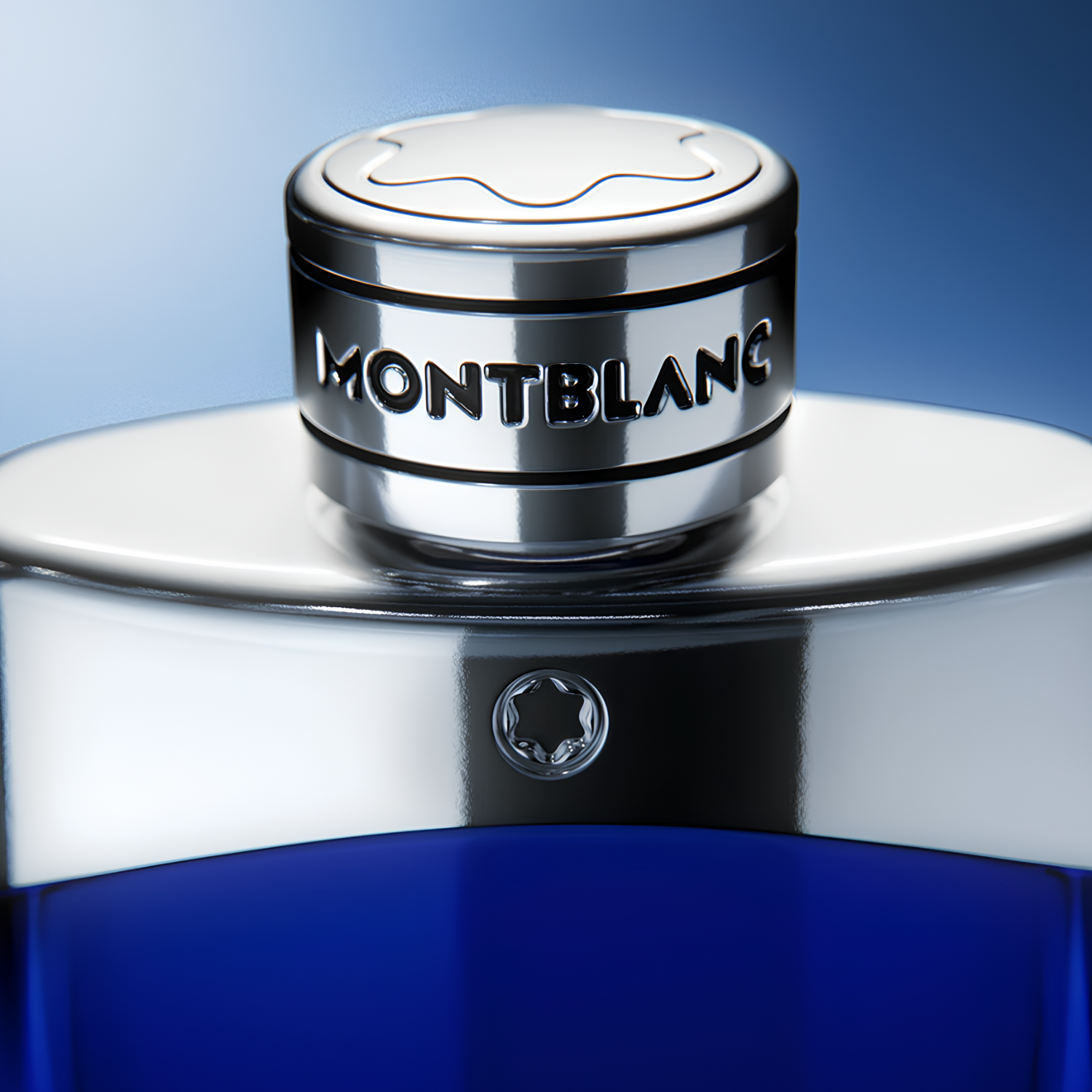 Close-up da tampa prateada do perfume Legend Blue Montblanc, destacando o logo da estrela em relevo e a inscrição "MONTBLANC" em letras pretas.
