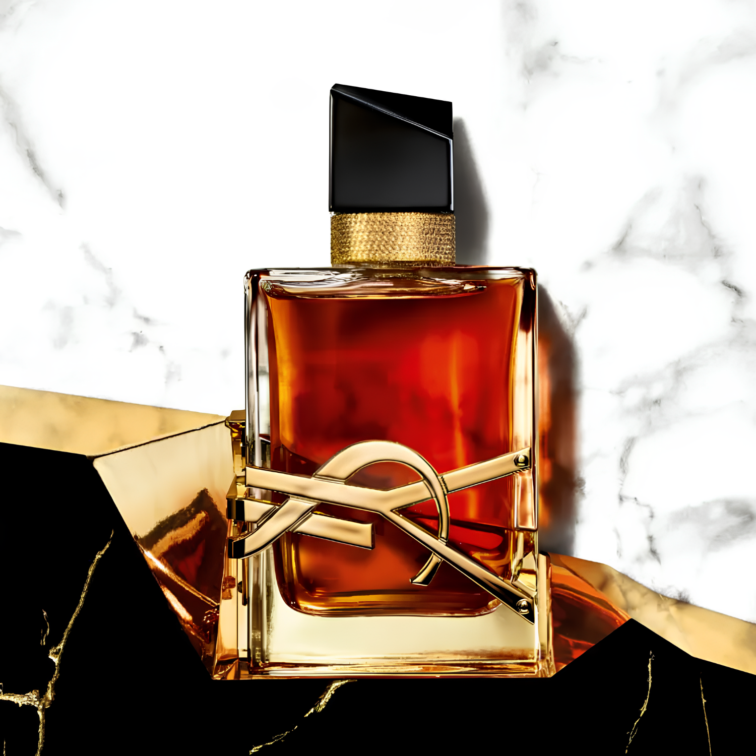 Perfume feminino Libre Saint Laurent em destaque sobre uma superfície de mármore branco e preto com veias douradas, complementado por formas geométricas douradas, transmitindo uma estética luxuosa e ousada.