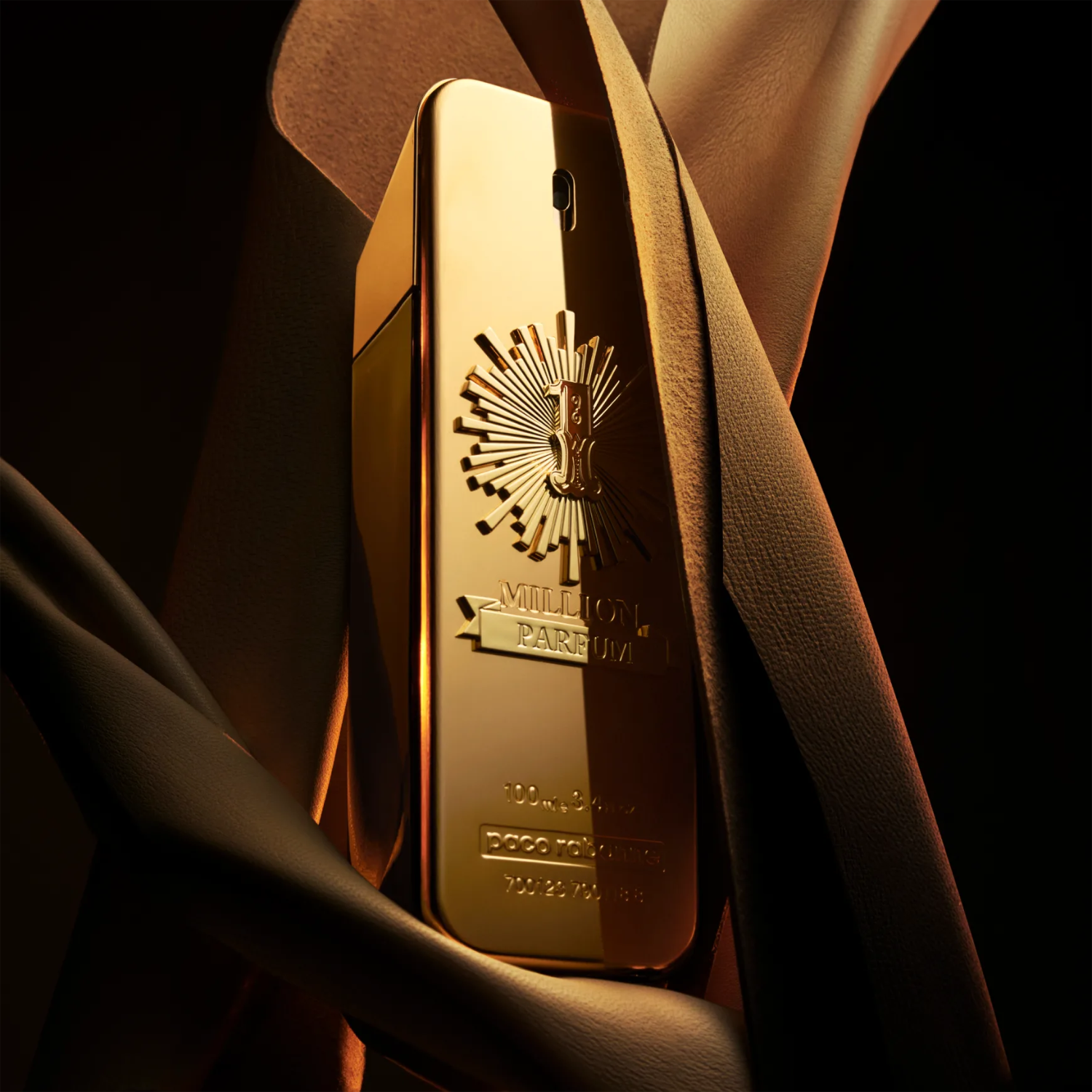Perfume importado masculino One Million Parfum Rabanne parcialmente envolto por um tecido dourado maleável, sugerindo luxo e sensualidade da fragrância, disponível na Velyre.