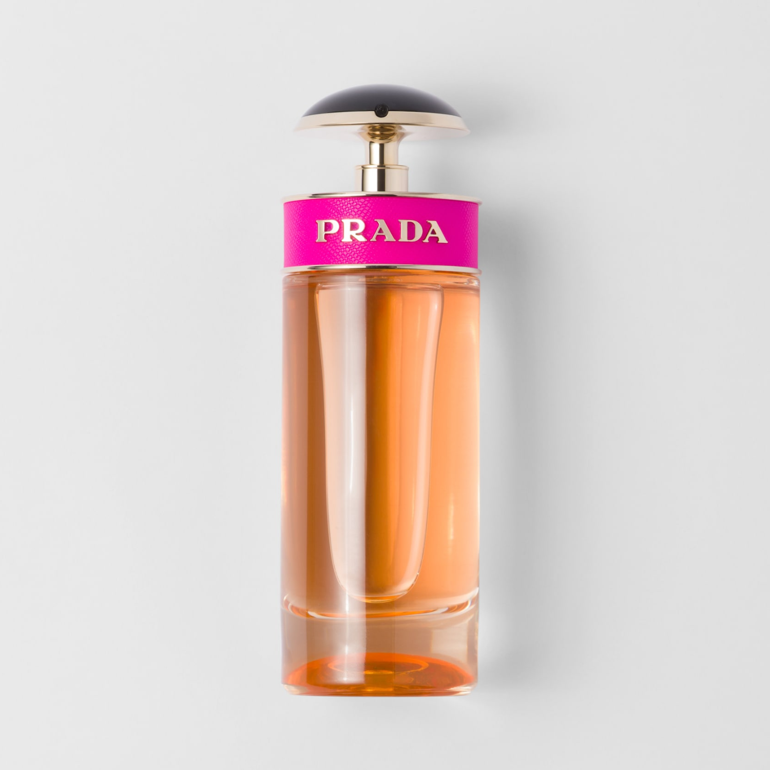 Perfume feminino Prada Candy Prada em destaque em um ambiente minimalista com um fundo cinza claro, realçando o design cilíndrico do frasco e a cor vibrante da fragrância.