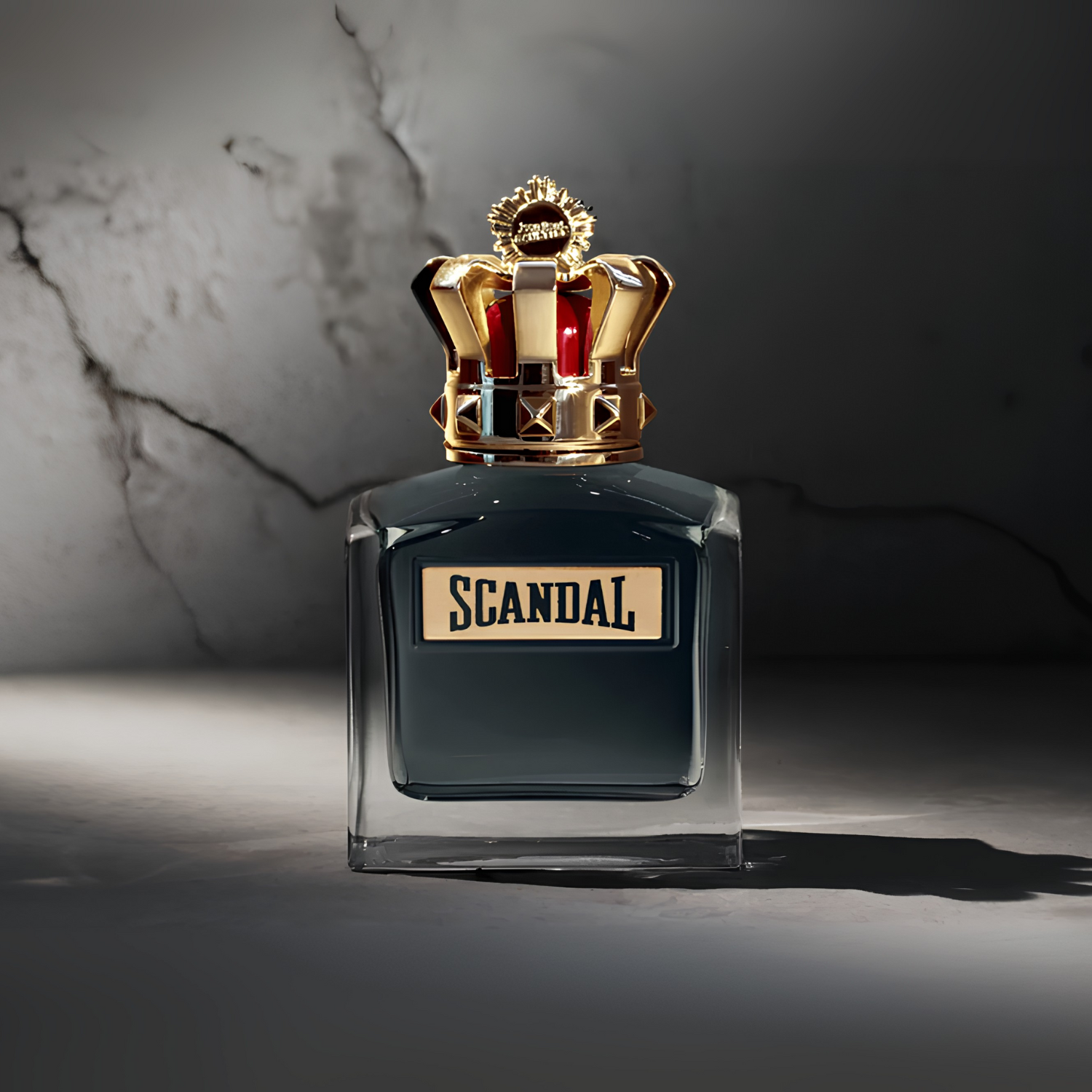 Perfume Scandal Pour Homme Jean Paul Gaultier em destaque sobre uma superfície de mármore com veios marcantes, realçando a elegância e a força do frasco e da coroa.