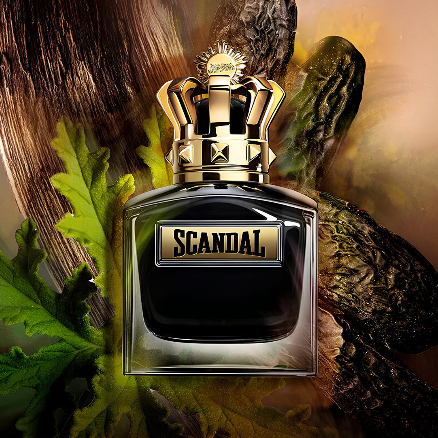 Frasco do Scandal Pour Homme Parfum de Jean Paul Gaultier em destaque sobre uma composição artística de folhas verdes e madeiras, realçando a proposta intensa e marcante da fragrância masculina.