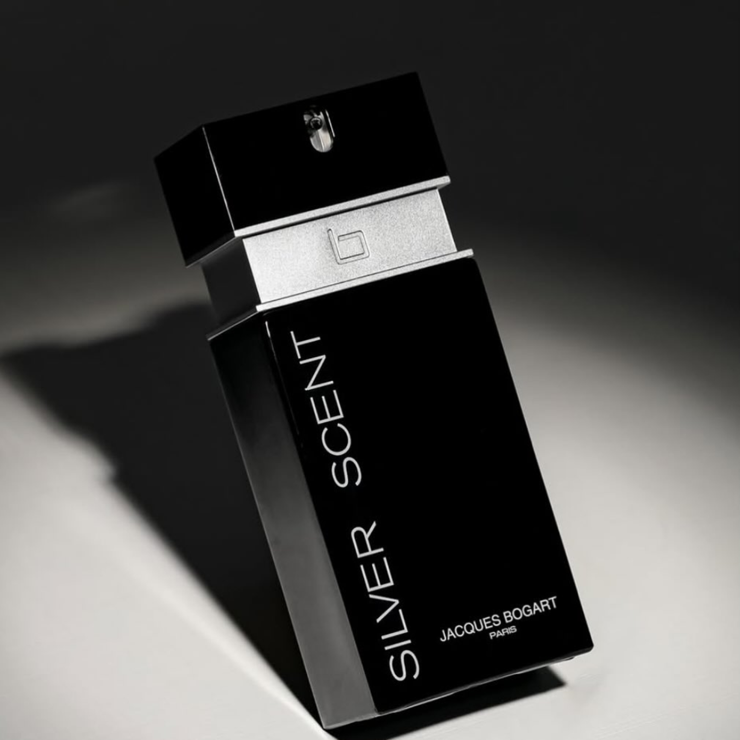 Perfume Silver Scent Jacques Bogart em ângulo dinâmico, com jogo de luz e sombra dramático, transmitindo sofisticação e mistério da fragrância masculina.