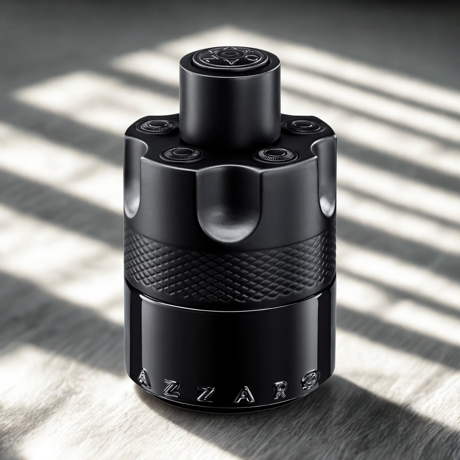 Perfume masculino The Most Wanted Azzaro em destaque sobre uma superfície de madeira clara, com luz e sombra que realçam a forma e a textura do frasco preto.