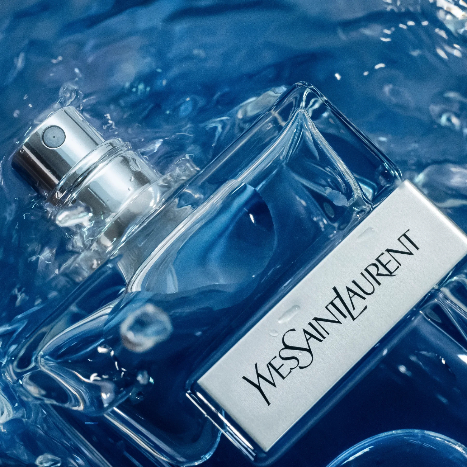 Perfume masculino Y Yves Saint Laurent flutuando em água azul com respingos, transmitindo uma sensação de frescor e dinamismo, ideal para a fragrância.